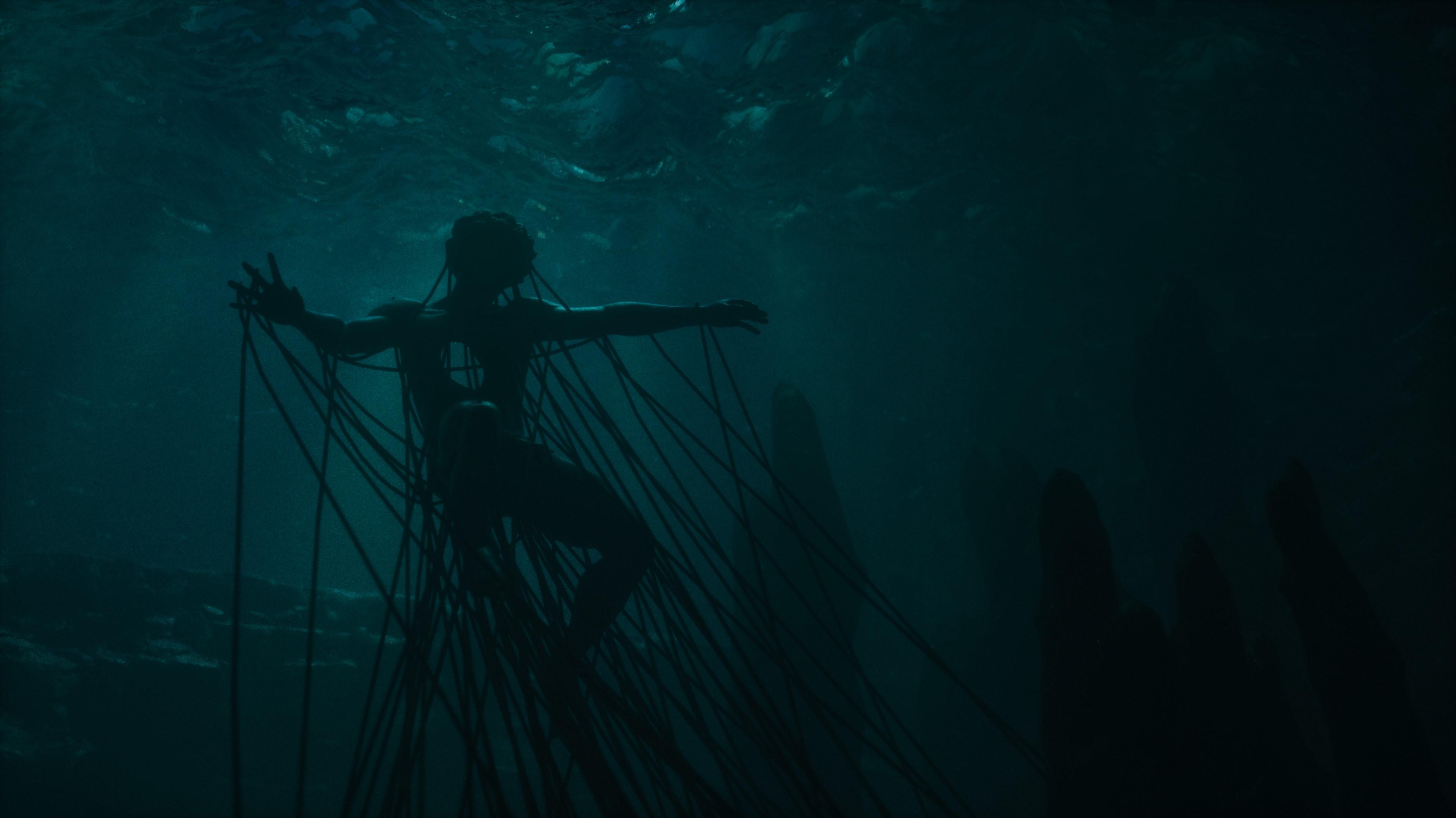 Silhouette of a person underwater connected by wires HD Wallpaper