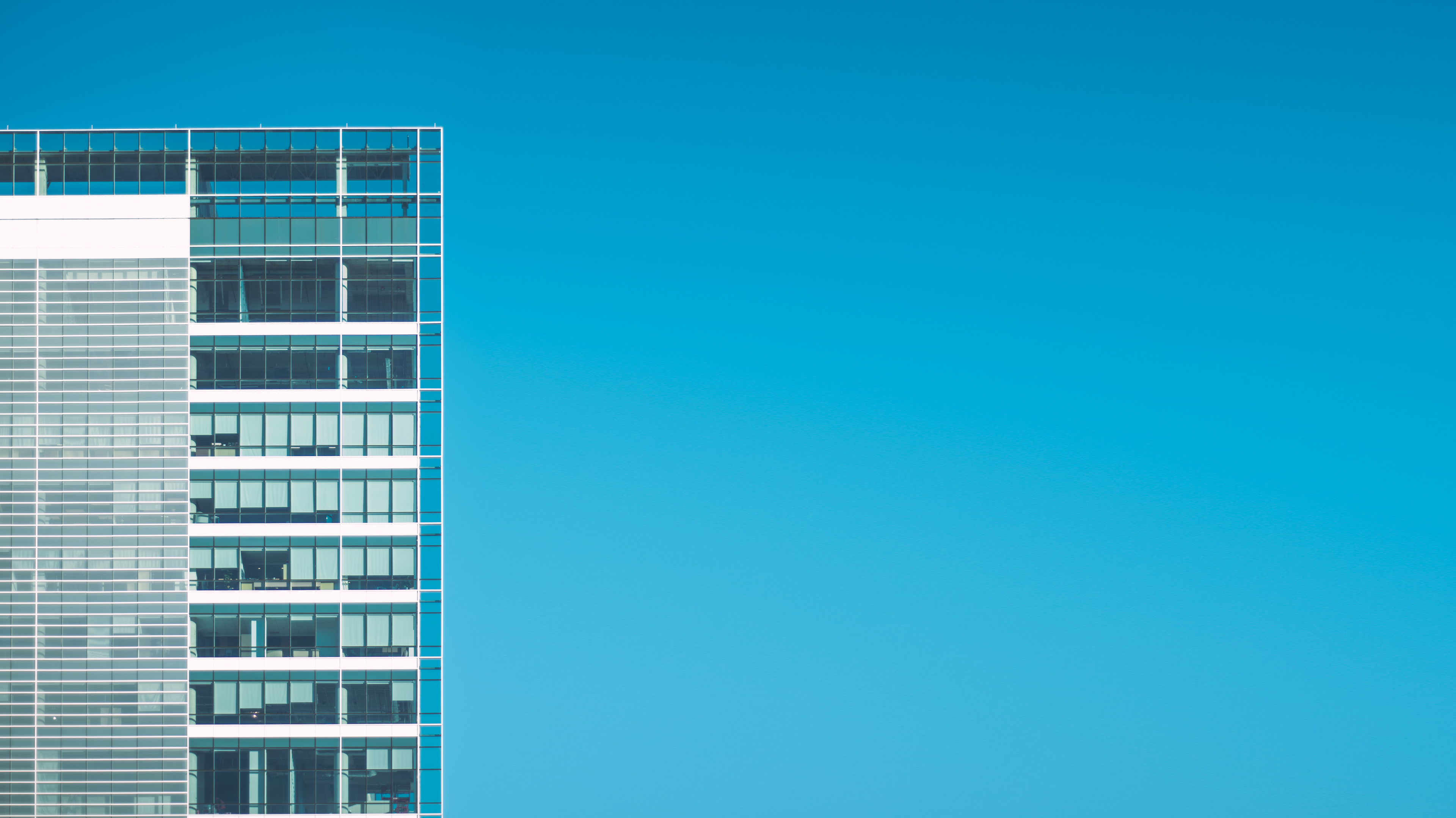 Modern glass building against a clear blue sky HD Wallpaper