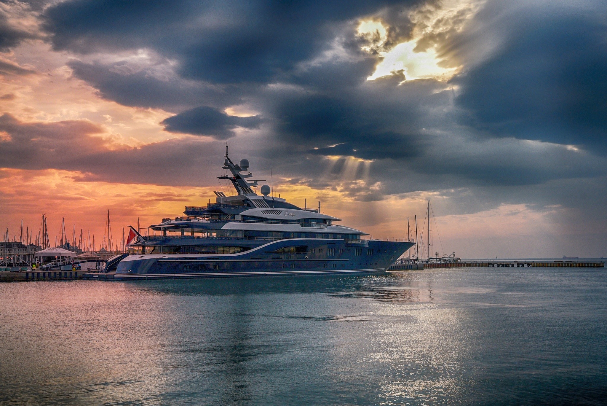 A large blue yacht docked in a harbor at sunset HD Wallpaper
