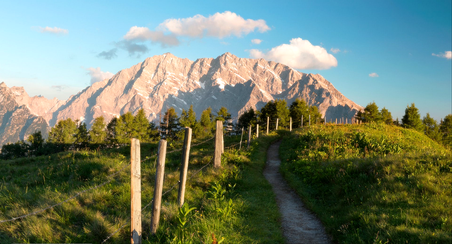 Mountain range with a path and fence HD Wallpaper
