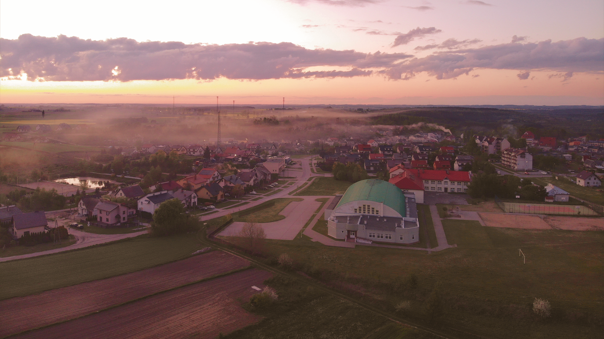 Aerial view of a town at sunset with mist HD Wallpaper