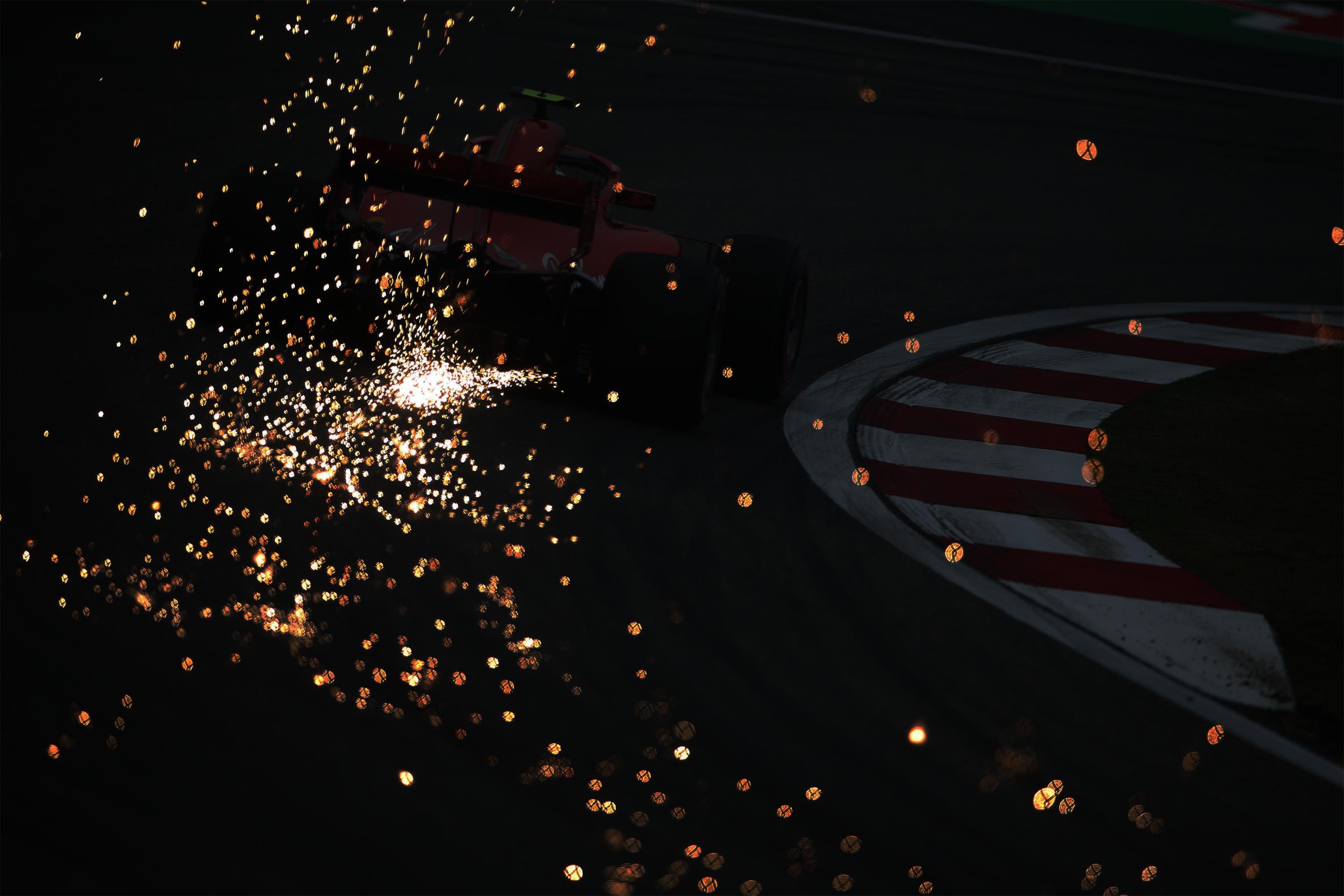 Formula 1 car with sparks on a dark track HD Wallpaper