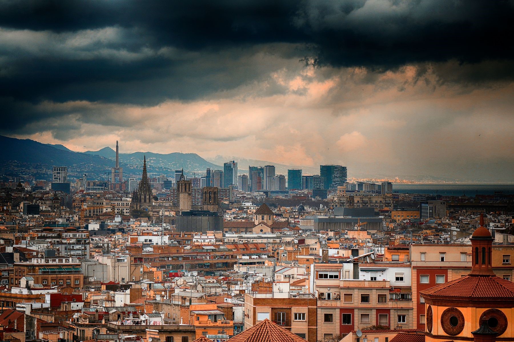 Barcelona cityscape under stormy clouds with mountains HD Wallpaper