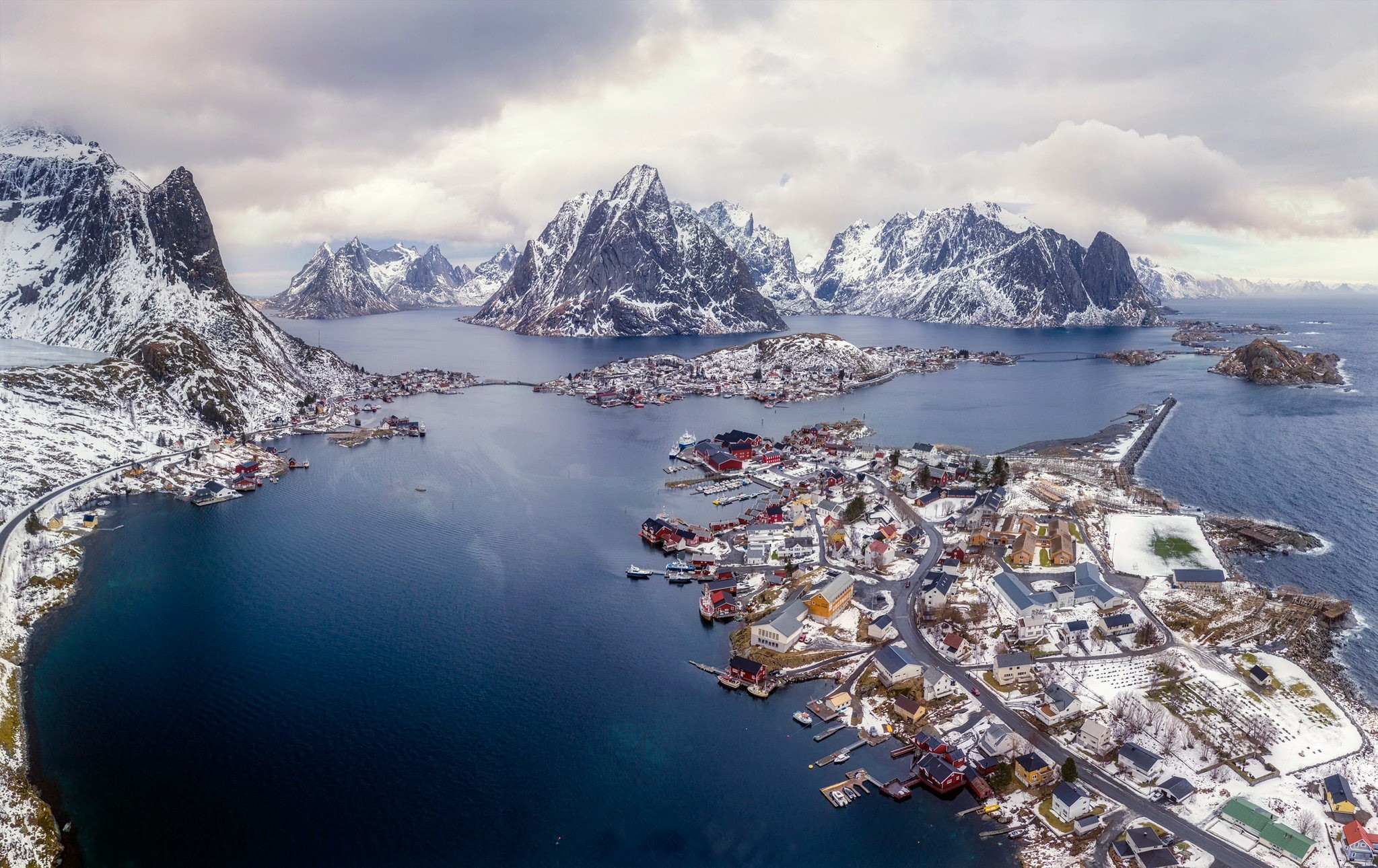 Aerial view of a snowy Norwegian village by the sea and mountains HD Wallpaper
