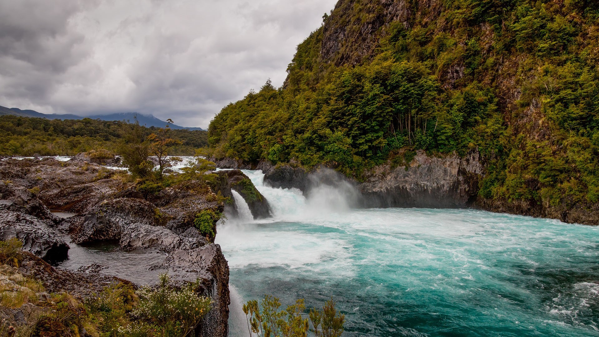 Waterfall flowing over rocks in a forest landscape HD Wallpaper