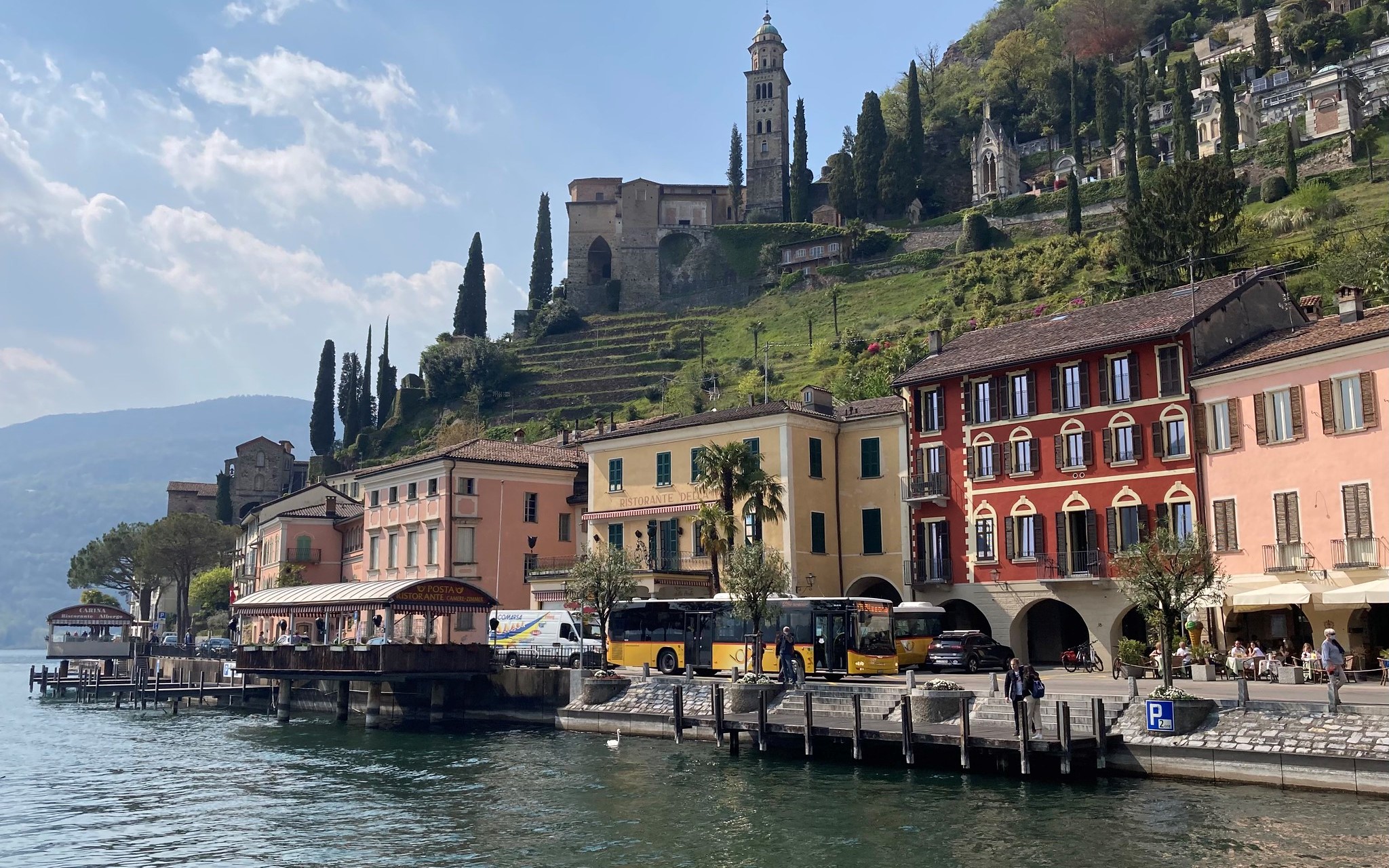 Lakeside town with terraced hills and a church tower HD Wallpaper