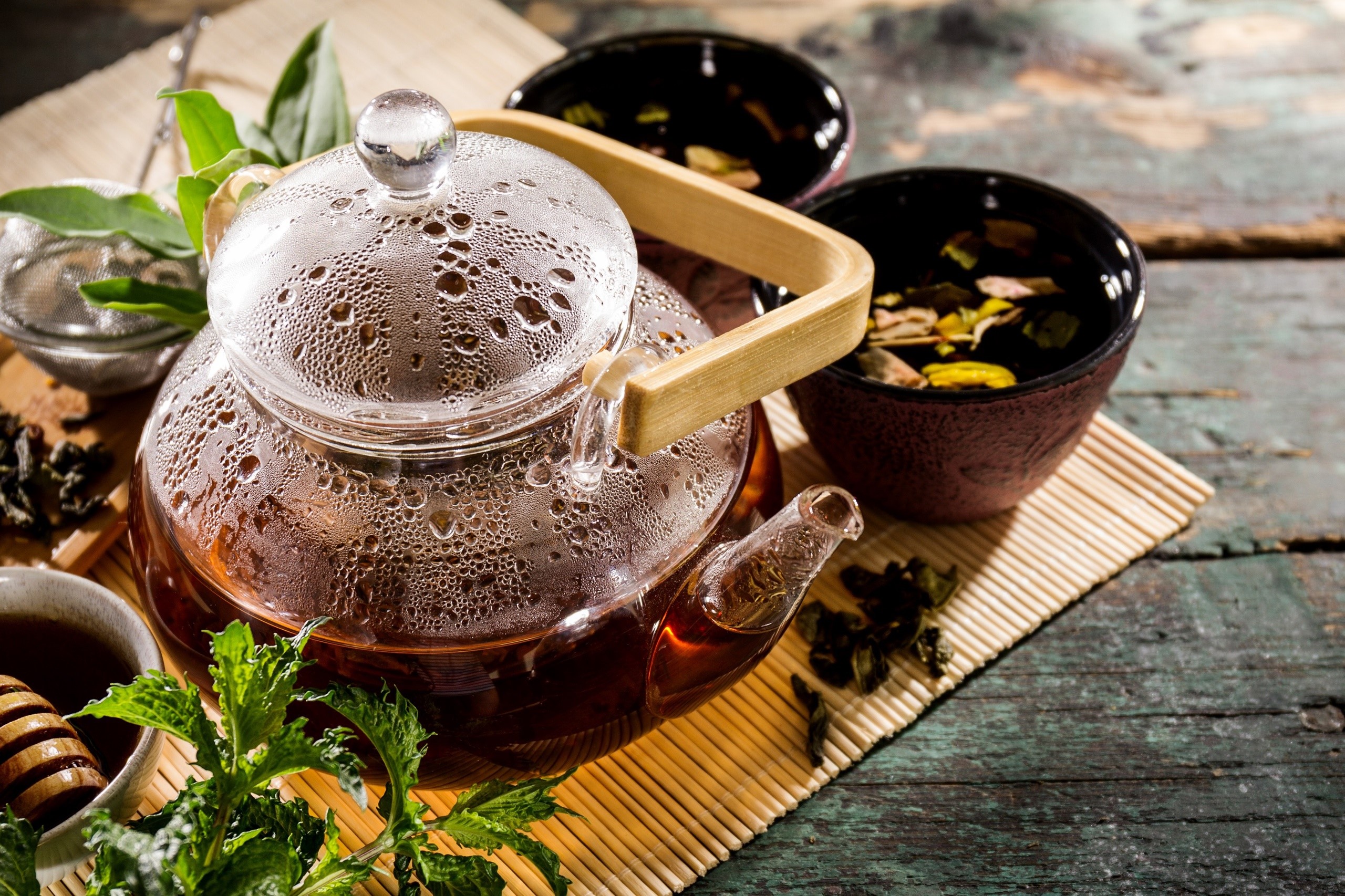 Glass teapot with tea and mint on a wooden surface HD Wallpaper