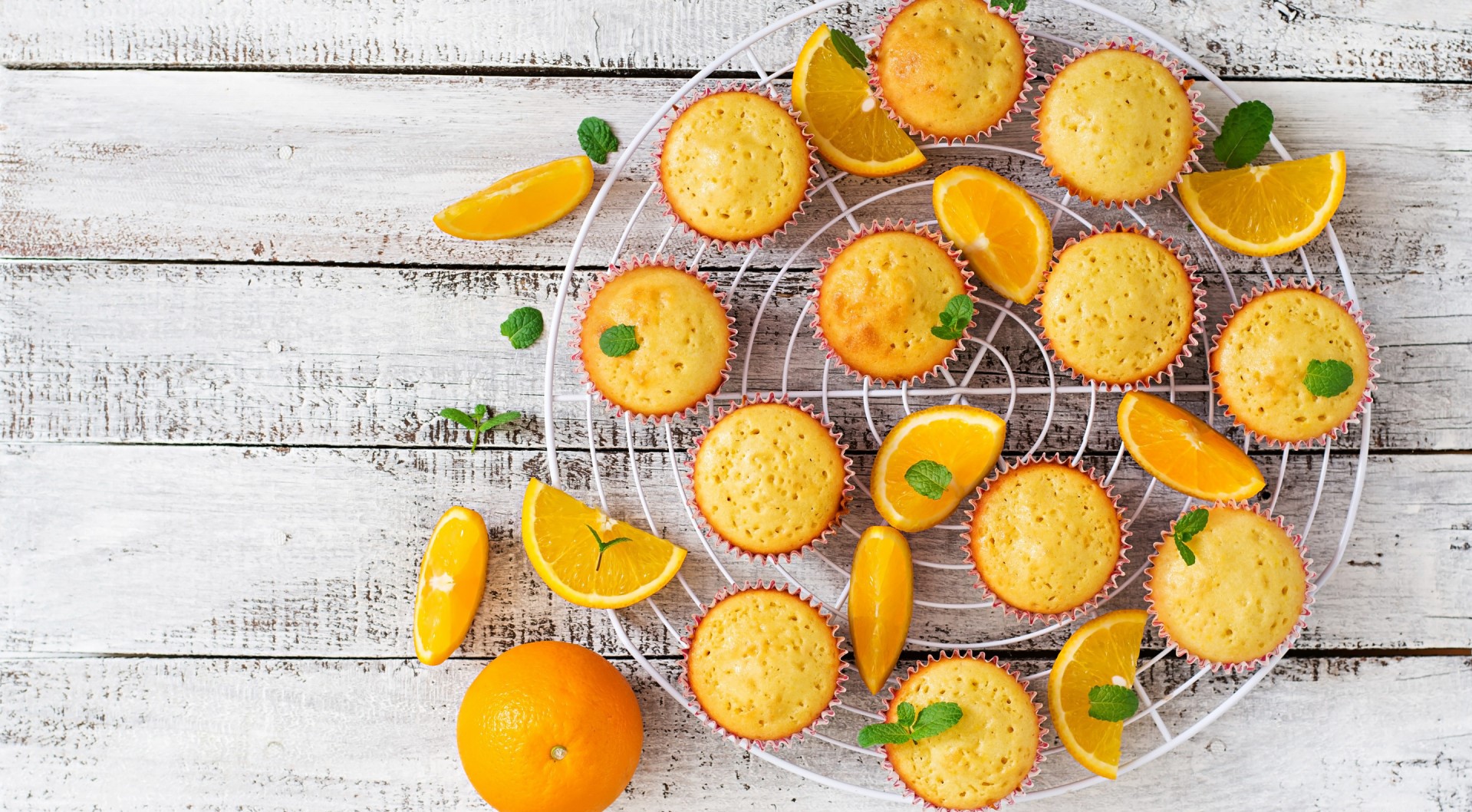 Orange muffins with mint and orange slices on a cooling rack HD Wallpaper
