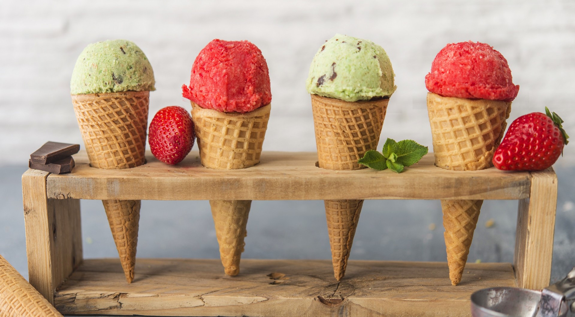 Four ice cream cones with strawberries and chocolate on a wooden stand HD Wallpaper