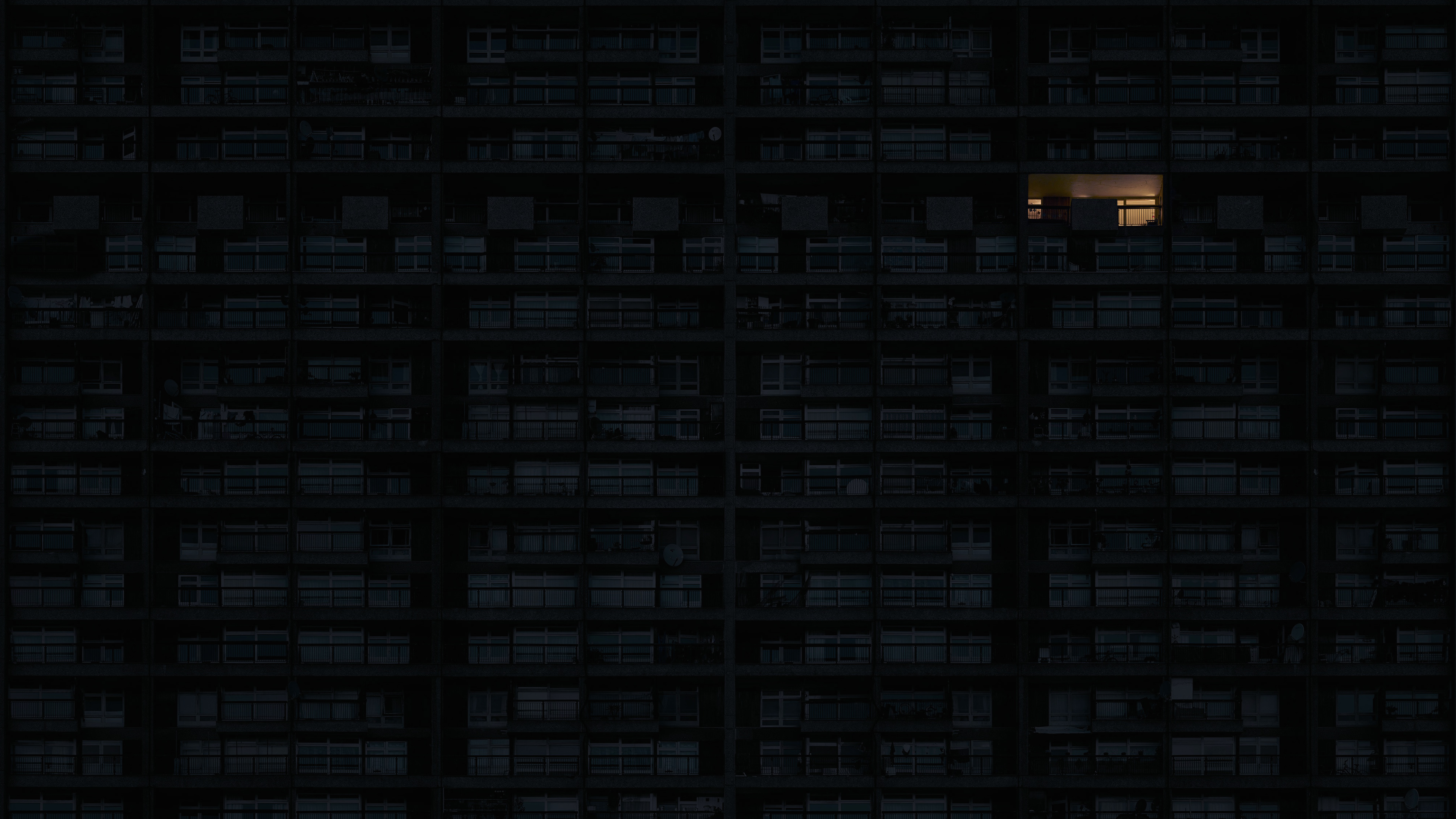 Apartment building at night with one lit window HD Wallpaper