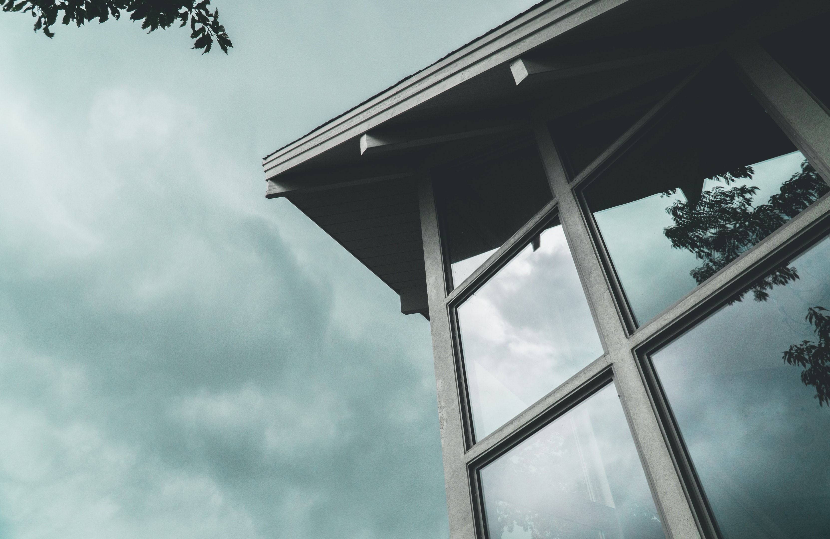 Low-angle view of a modern building with large windows under an overcast sky HD Wallpaper
