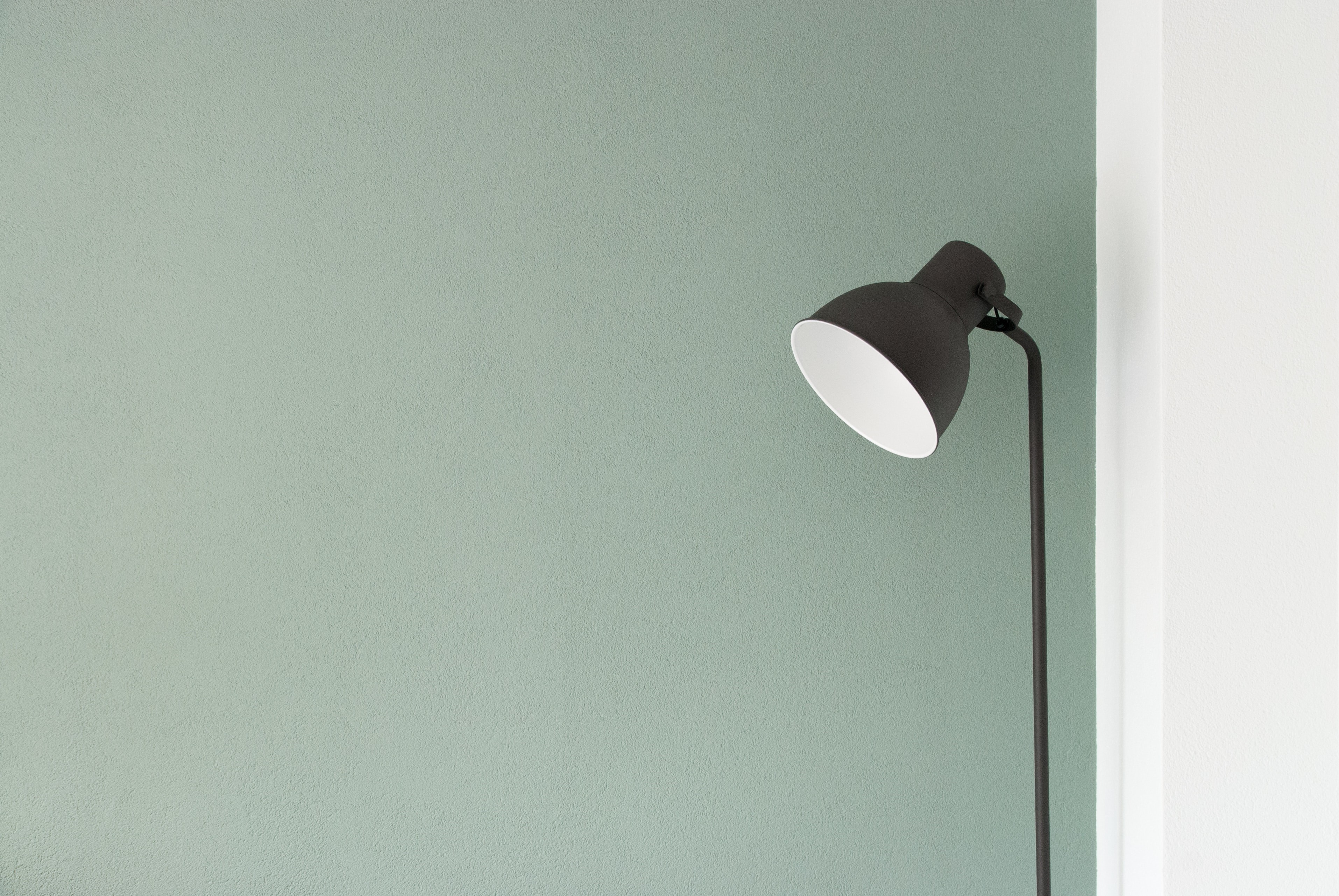 Minimalist floor lamp against a textured wall HD Wallpaper