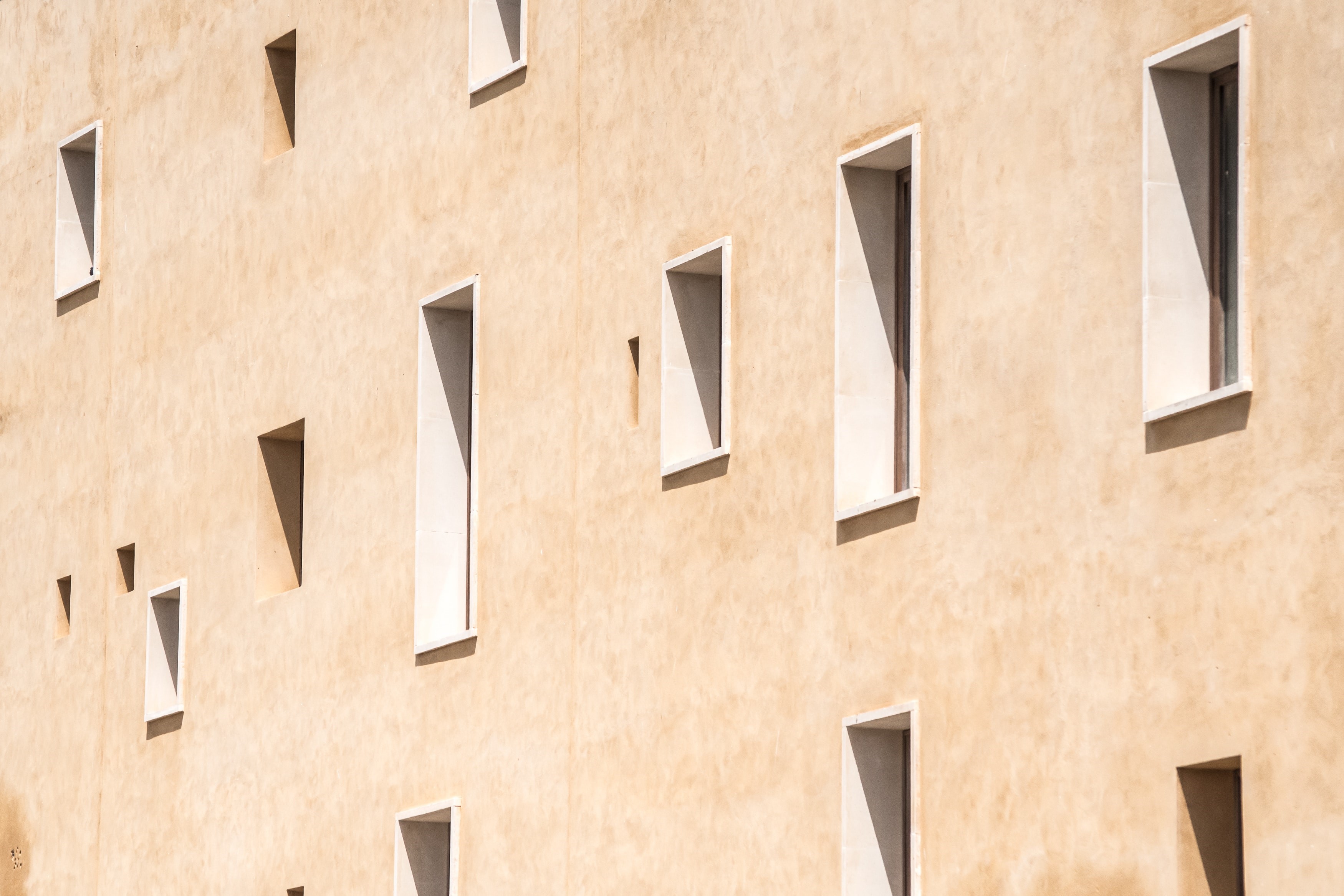 Beige building facade with numerous rectangular windows HD Wallpaper