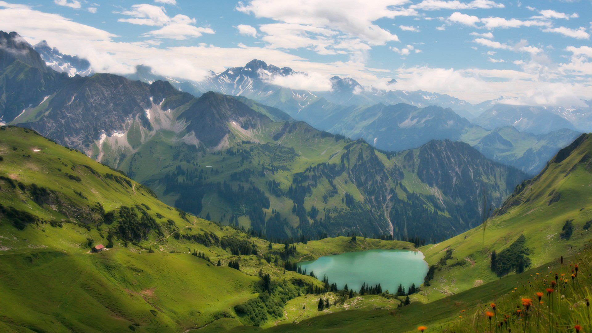 Turquoise lake nestled in green mountains under a cloudy sky HD Wallpaper