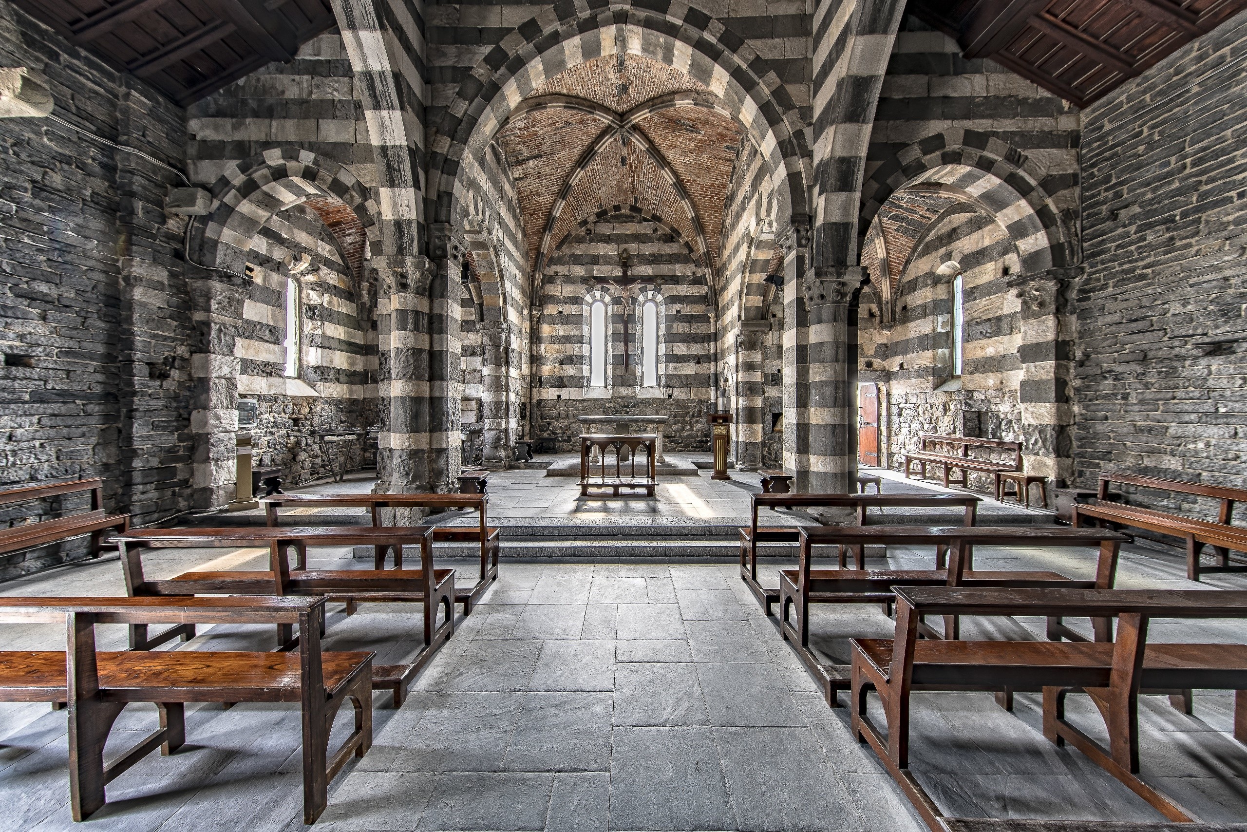Interior of a striped stone church with wooden pews HD Wallpaper