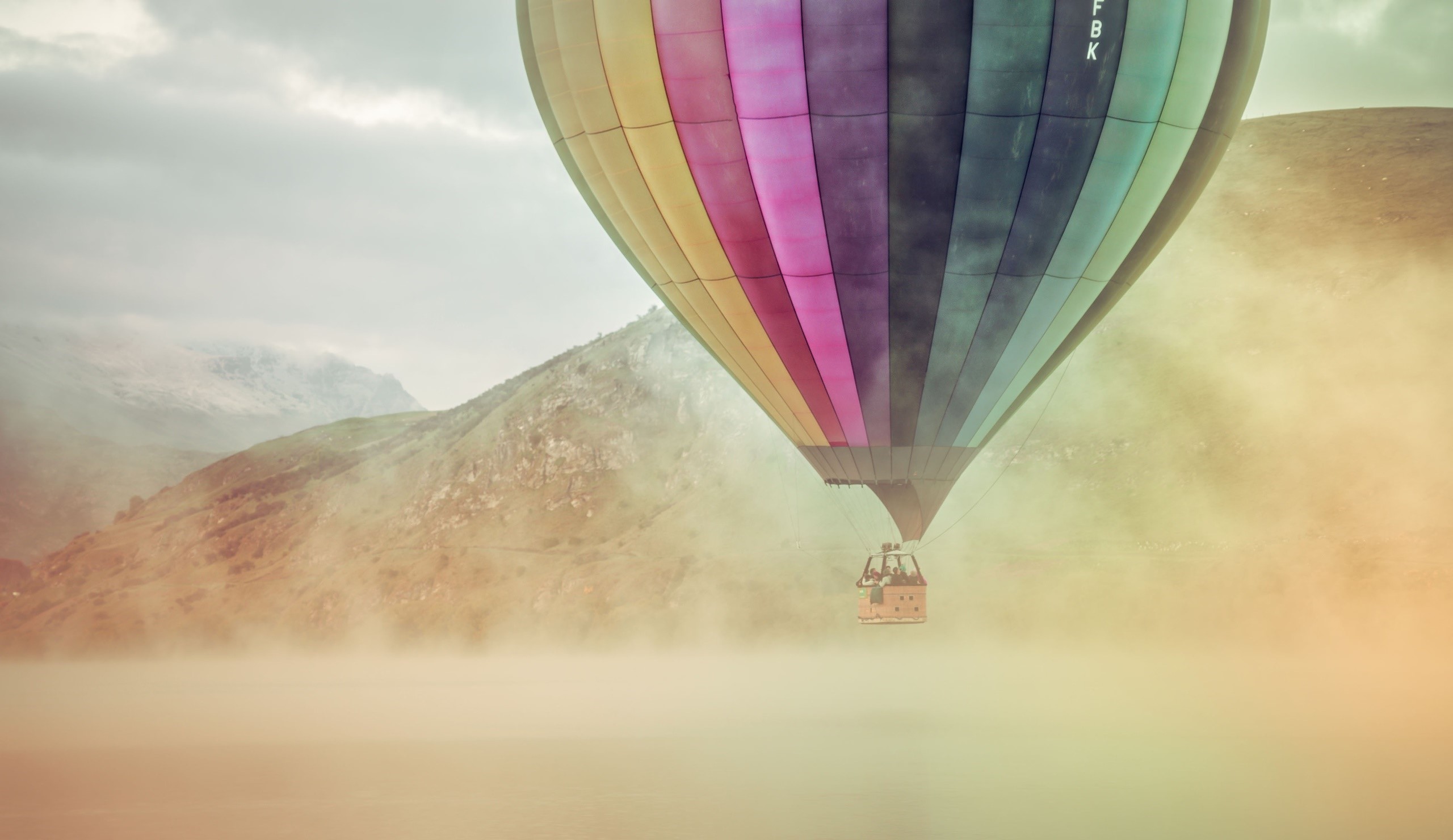 Colorful hot air balloon flying over misty mountains HD Wallpaper