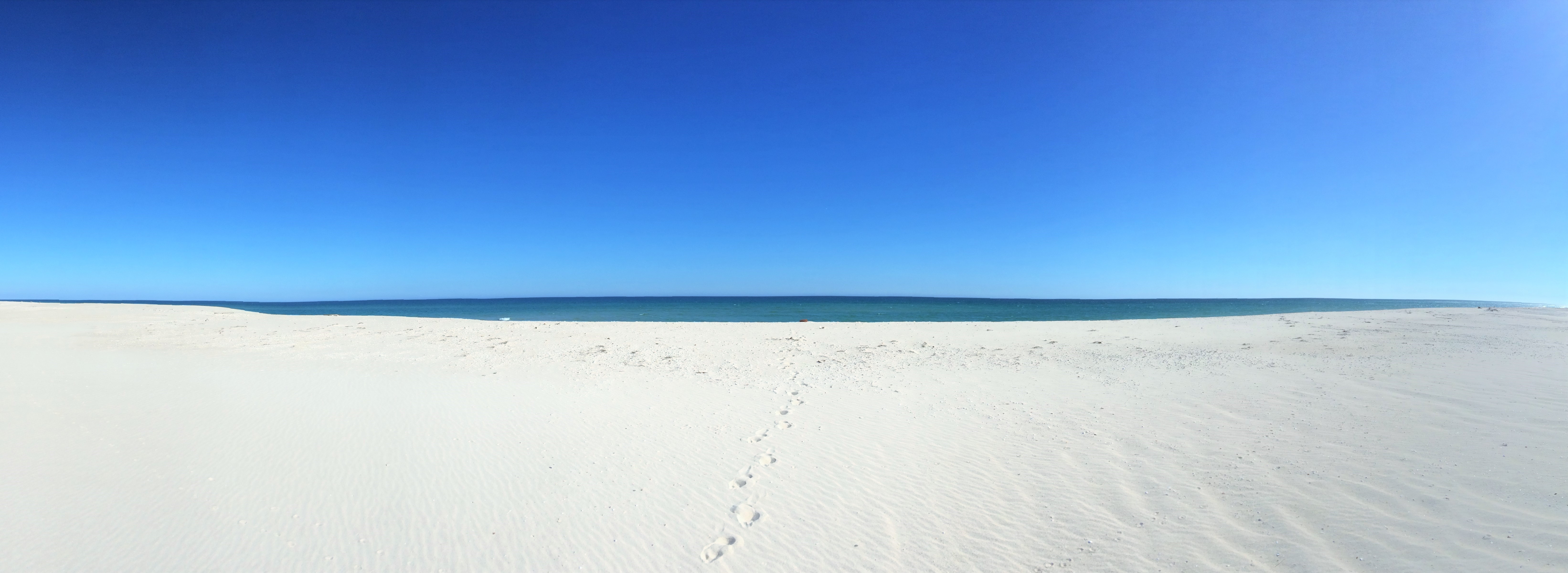 Footprints on a white sand beach with blue sky and sea HD Wallpaper