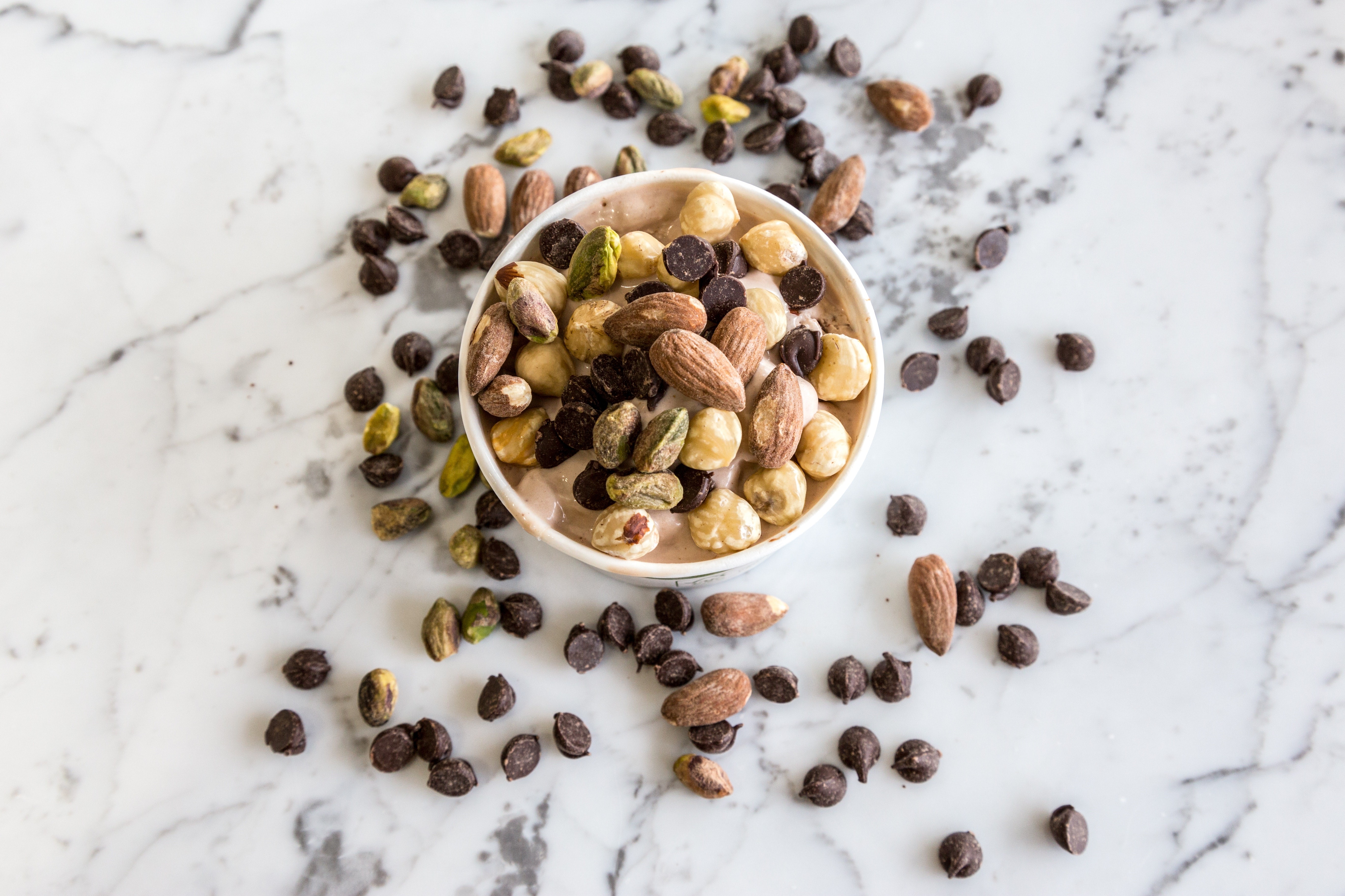 Bowl of nuts and chocolate chips on marble HD Wallpaper