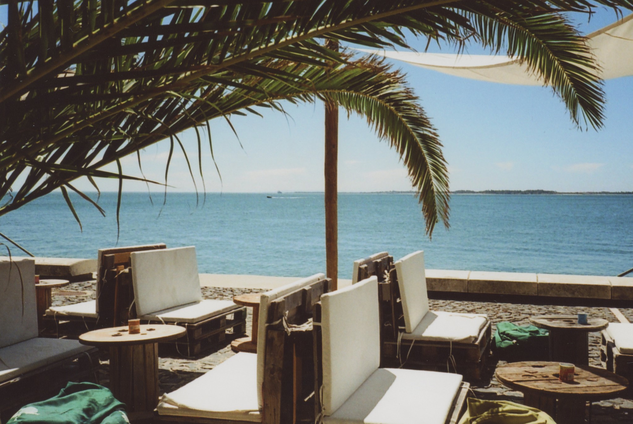 Outdoor seating area with ocean view and palm trees HD Wallpaper