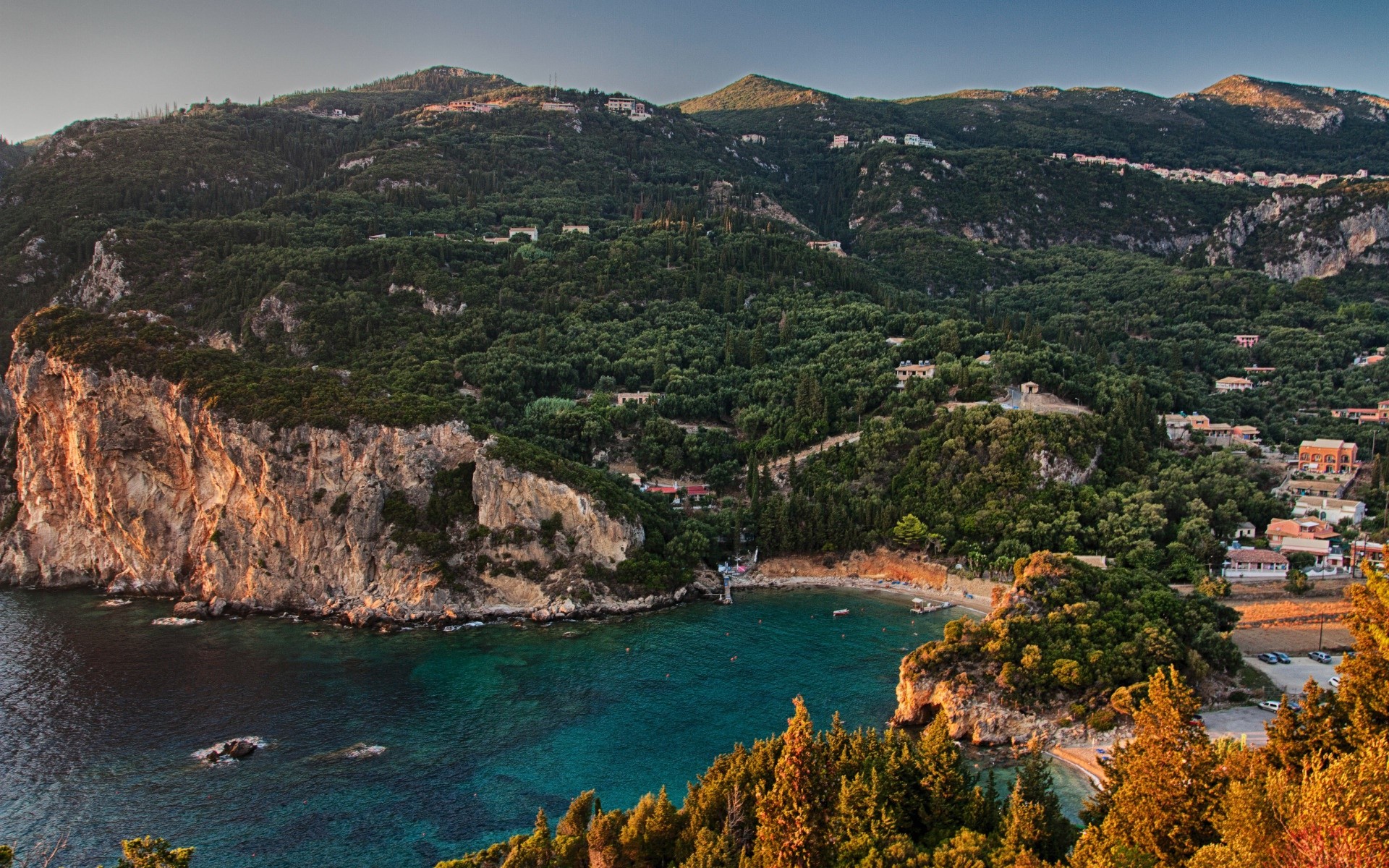 Coastal cliffs and bay with trees and houses HD Wallpaper