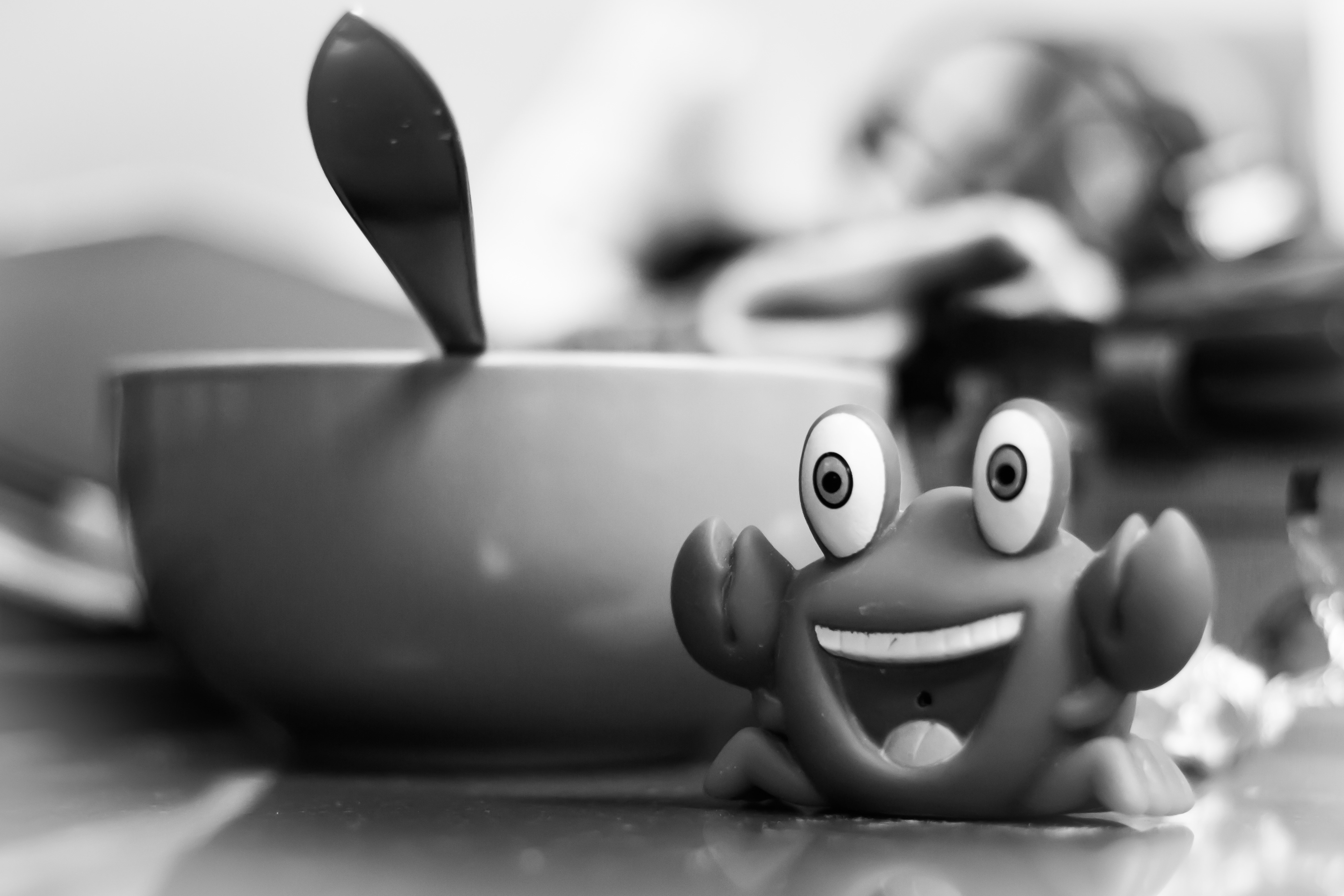 Monochrome toy crab next to a cup and spoon HD Wallpaper