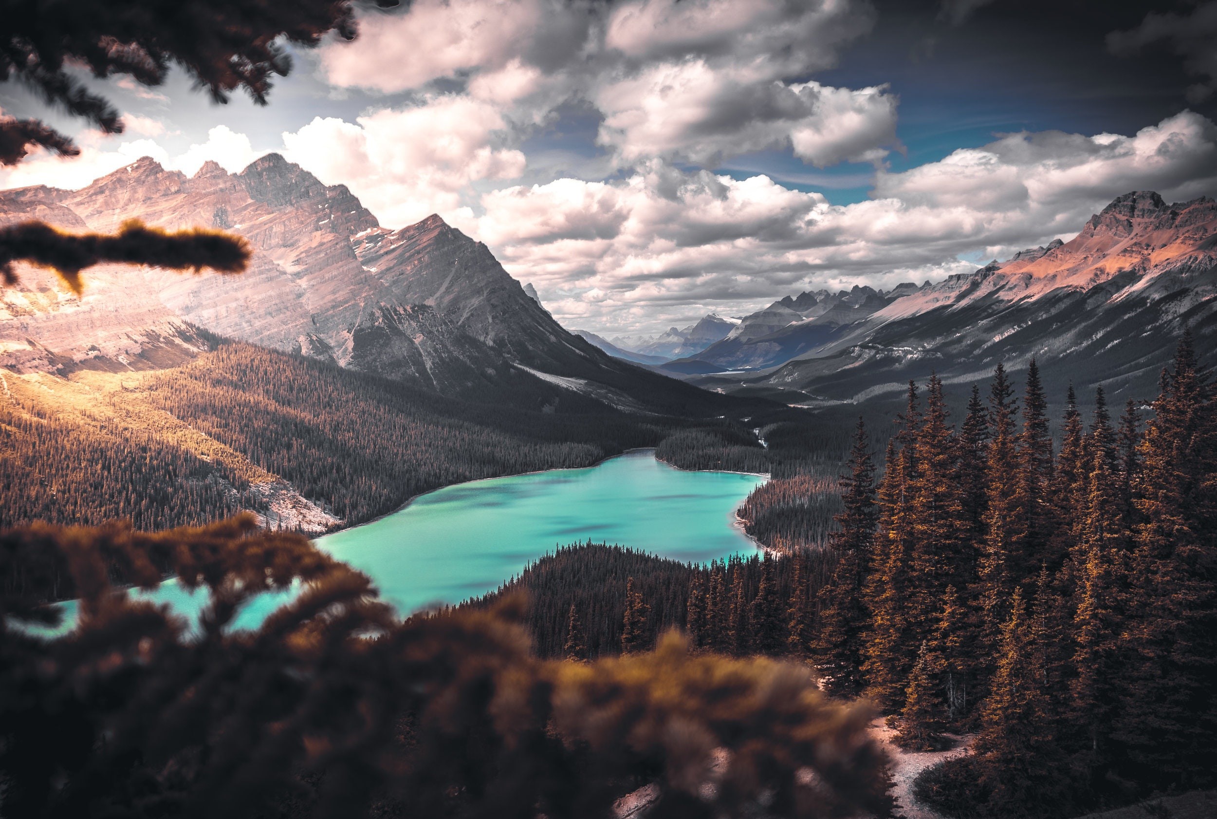 Turquoise lake surrounded by pine forest and mountains under cloudy sky HD Wallpaper