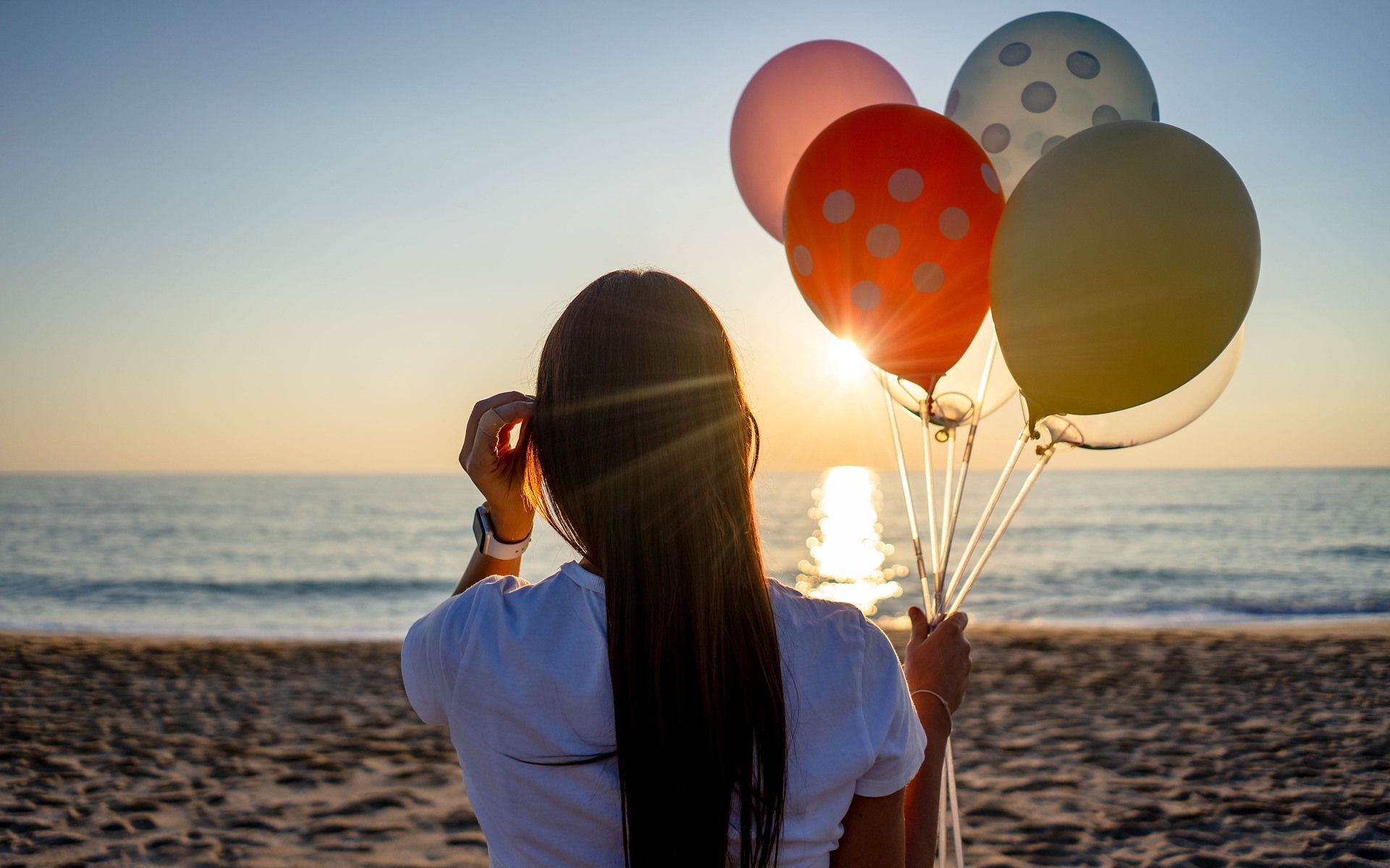Woman holding balloons at sunset on the beach HD Wallpaper
