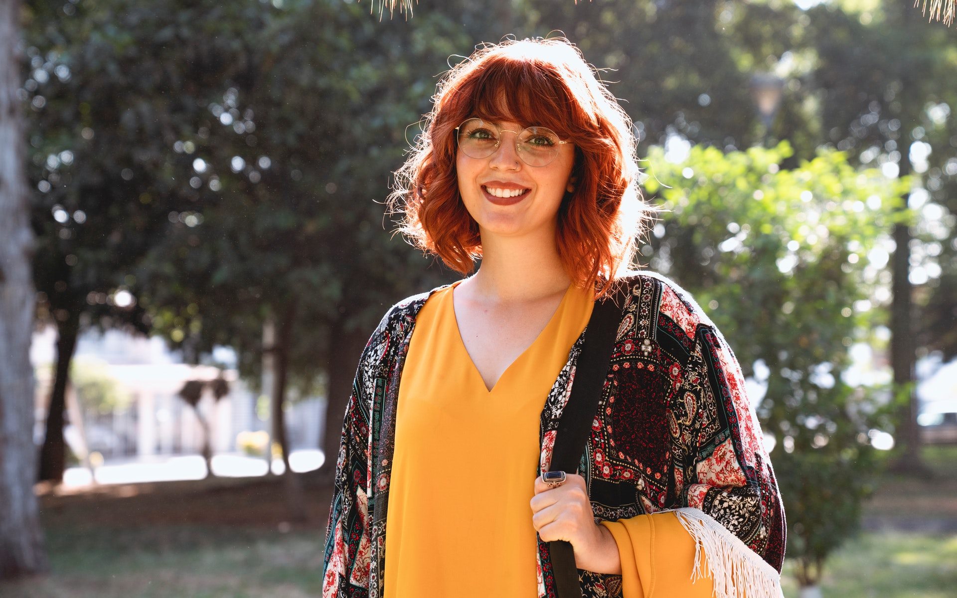 Redhead woman with glasses smiling outdoors HD Wallpaper