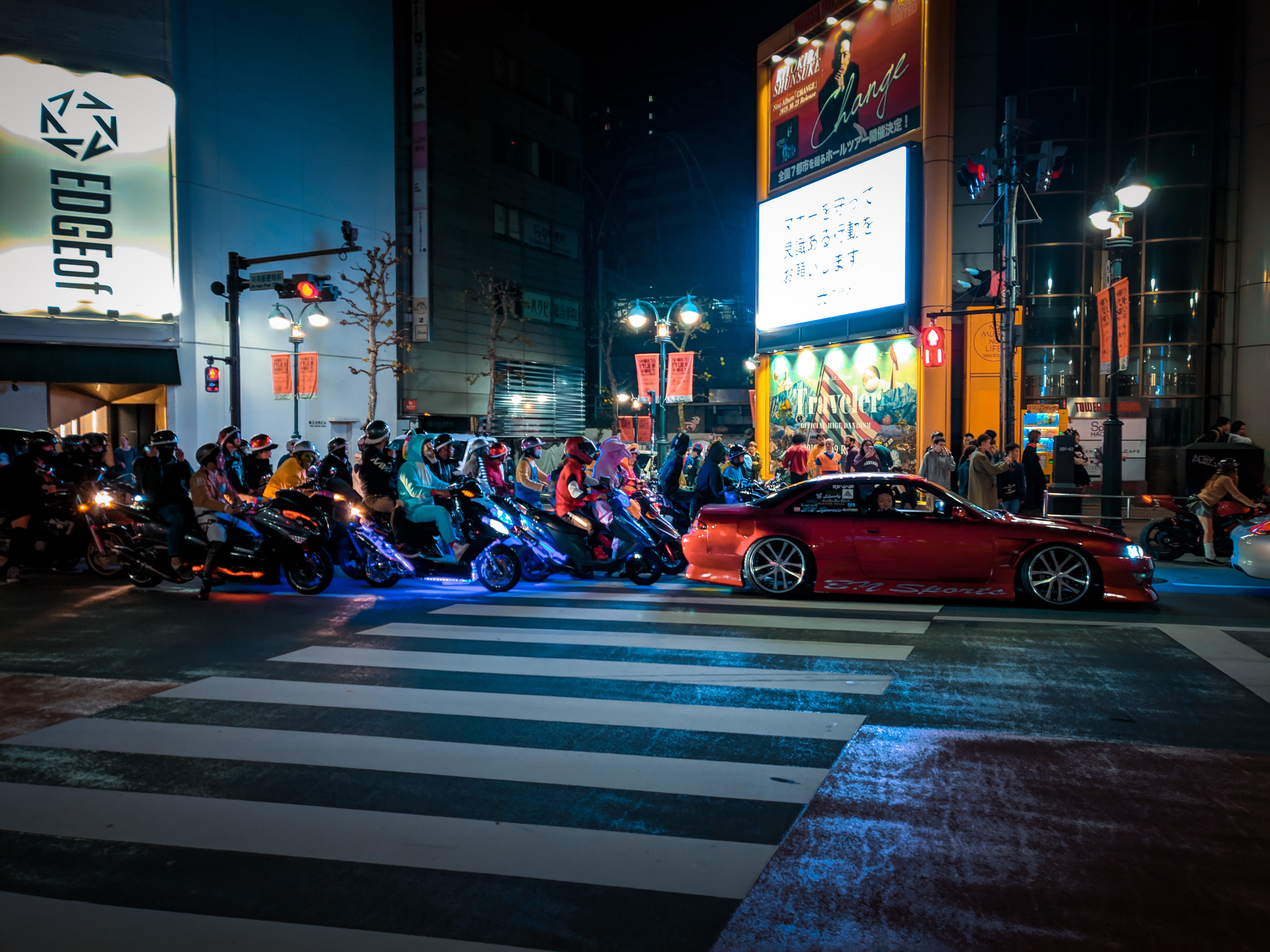 Night street scene with scooters and a red car in Japan HD Wallpaper