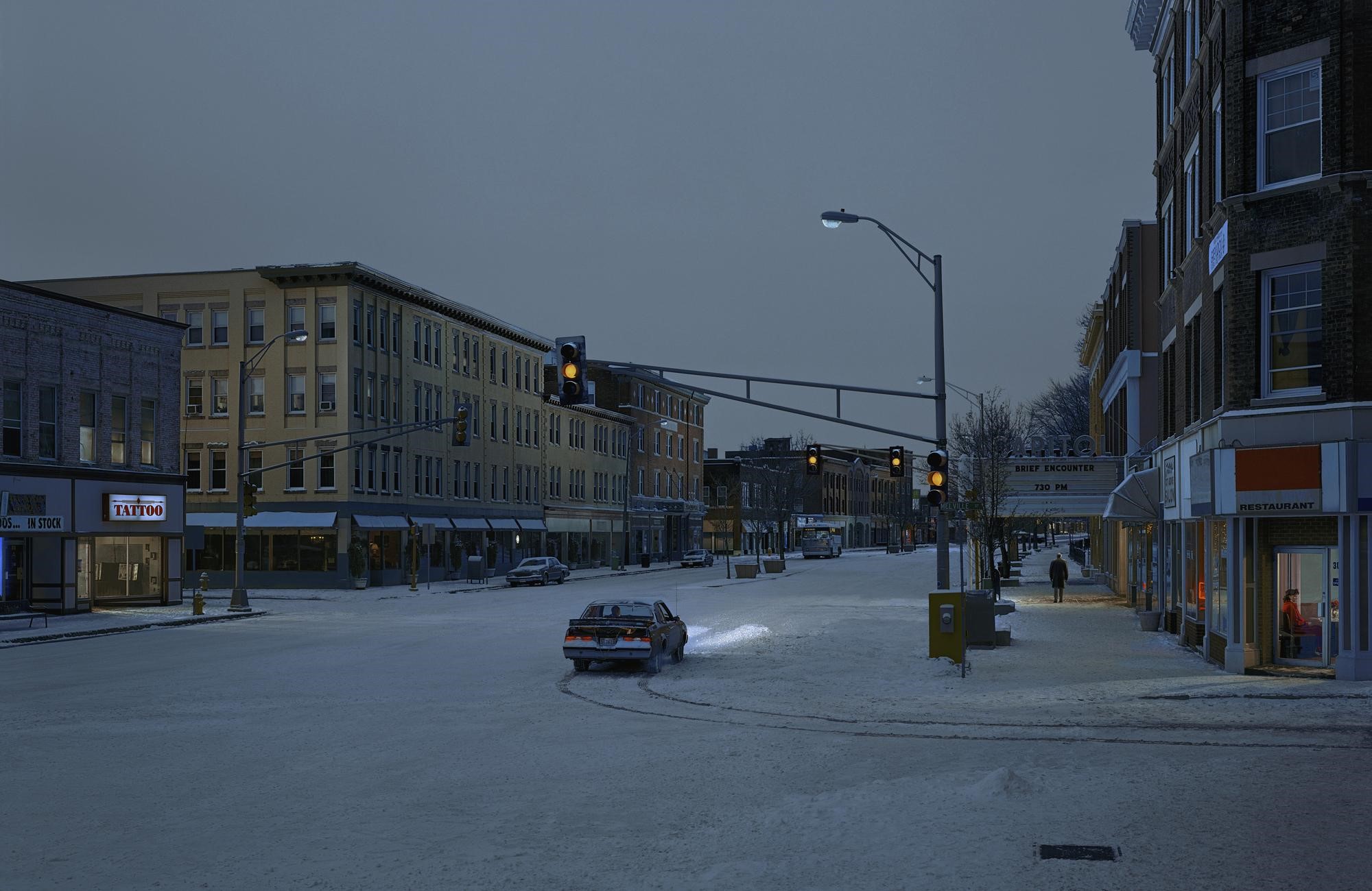 Snowy city street at dusk with traffic lights and buildings HD Wallpaper