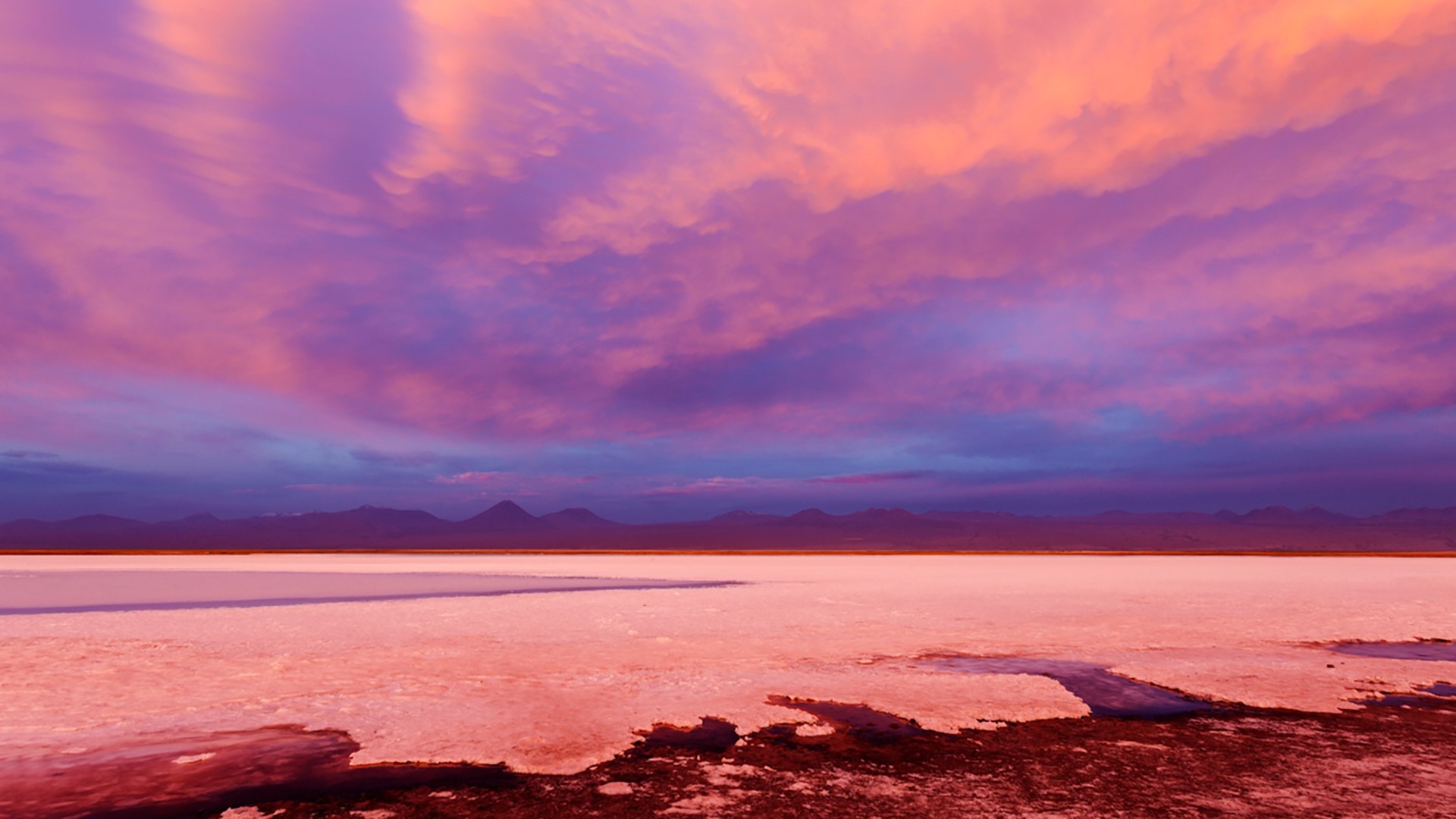Pink and purple clouds over a salt flat landscape at sunset HD Wallpaper