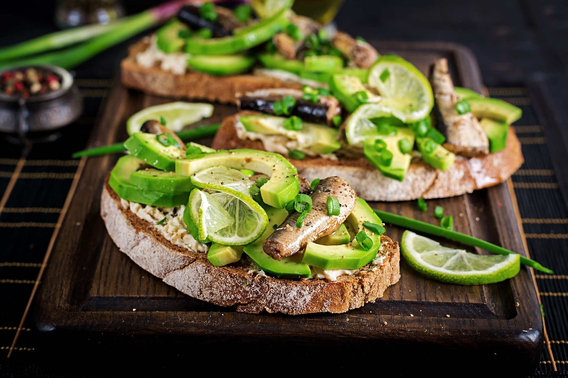 Avocado toast with sardines and lime on a cutting board HD Wallpaper