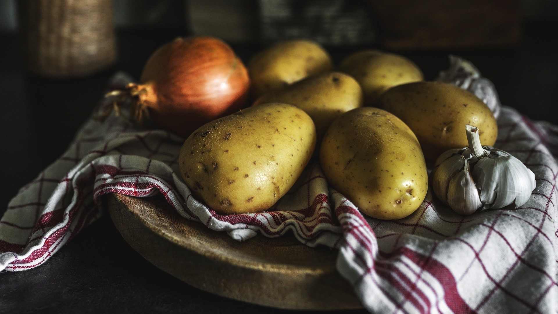 Still life of potatoes, onion, and garlic on a checkered cloth HD Wallpaper