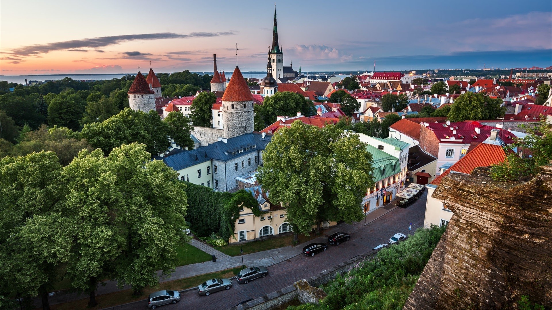 Tallinn Old Town skyline at sunset with trees and cars HD Wallpaper