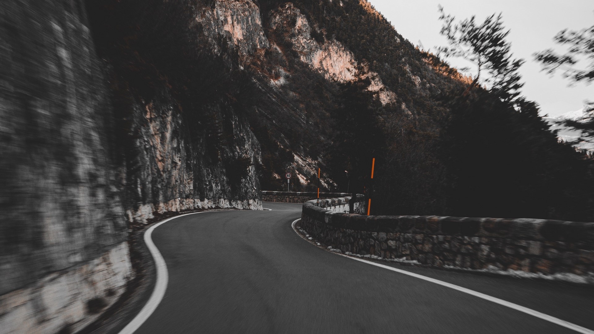 Curved mountain road with stone wall HD Wallpaper