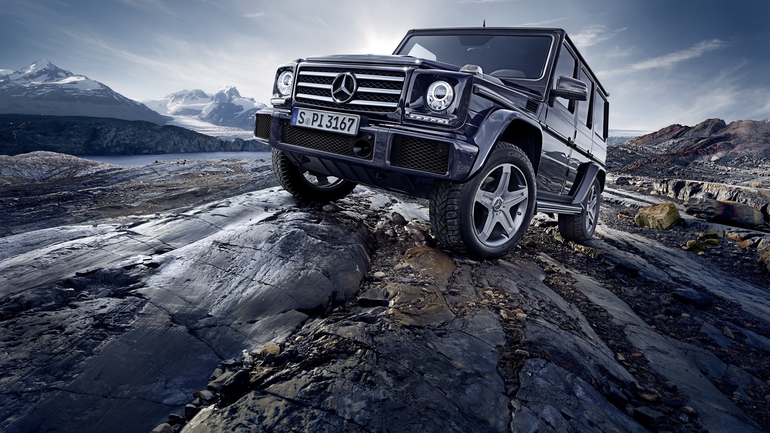 Mercedes-Benz G-Class driving on rocky terrain with mountains HD Wallpaper