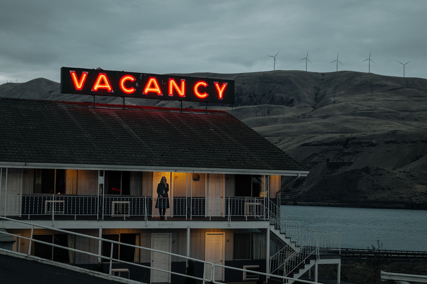 Motel with Vacancy neon sign and woman on balcony HD Wallpaper