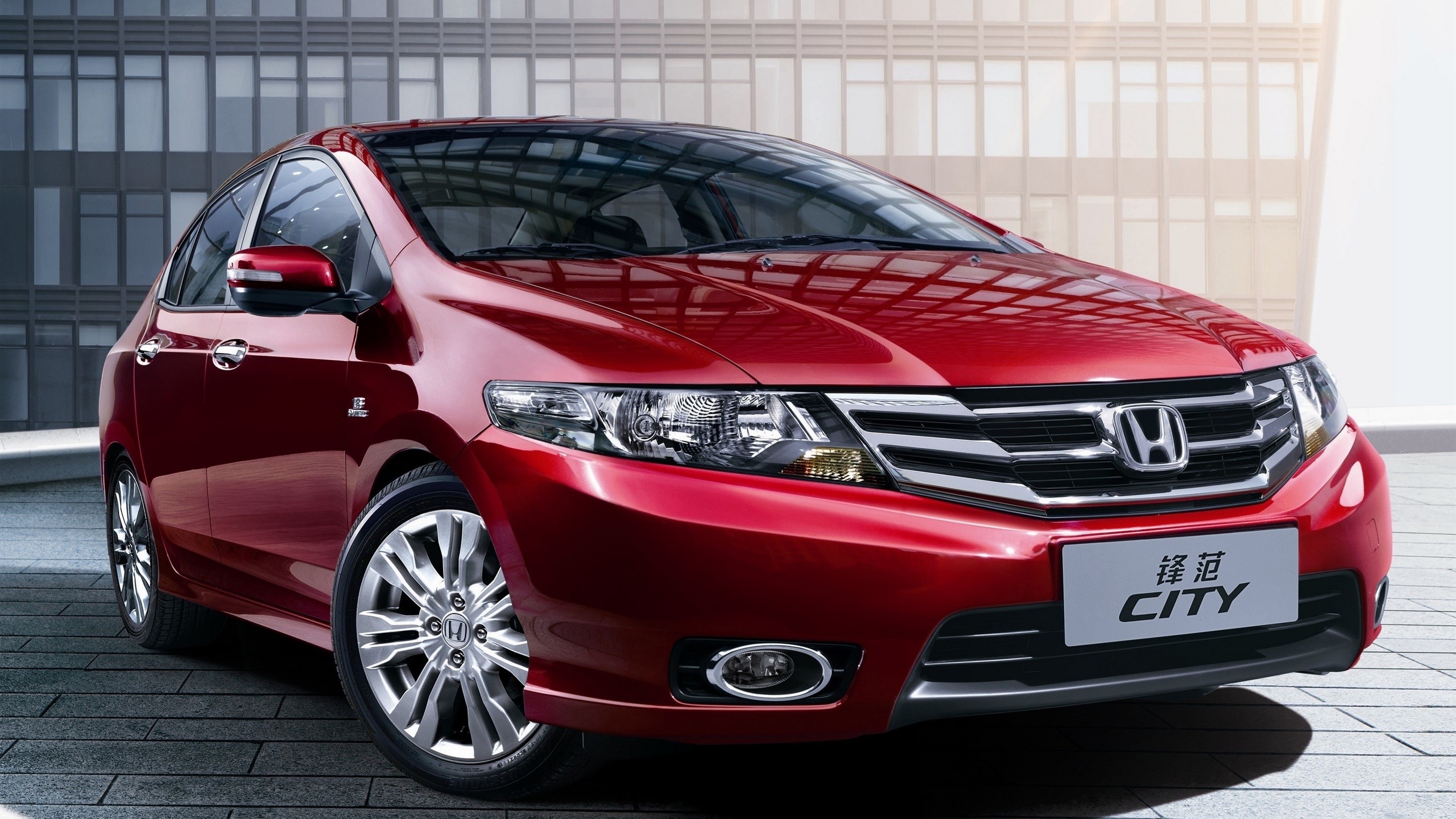 Red Honda City car parked in front of a modern building HD Wallpaper