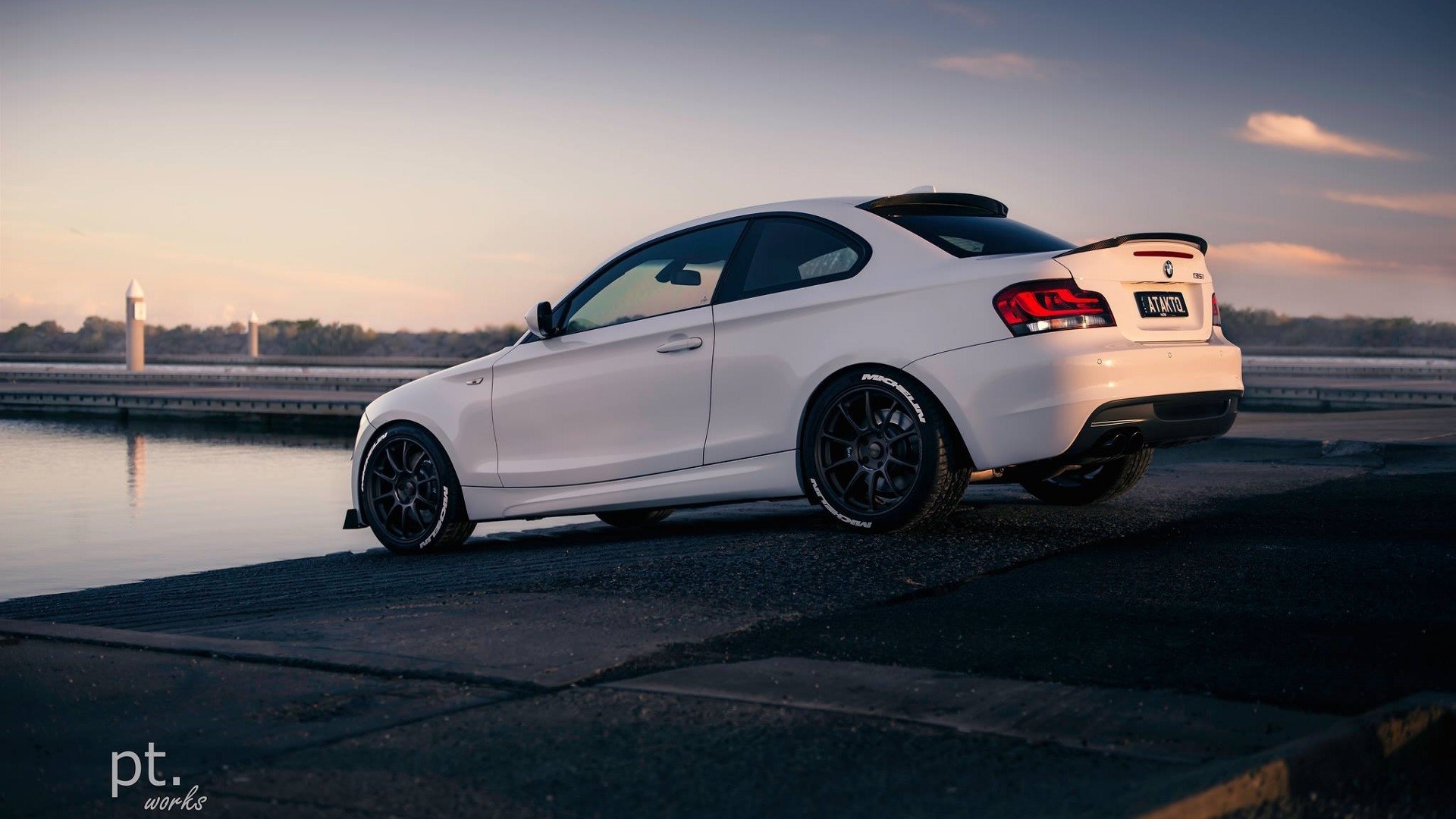 White BMW coupe parked by the water at sunset HD Wallpaper