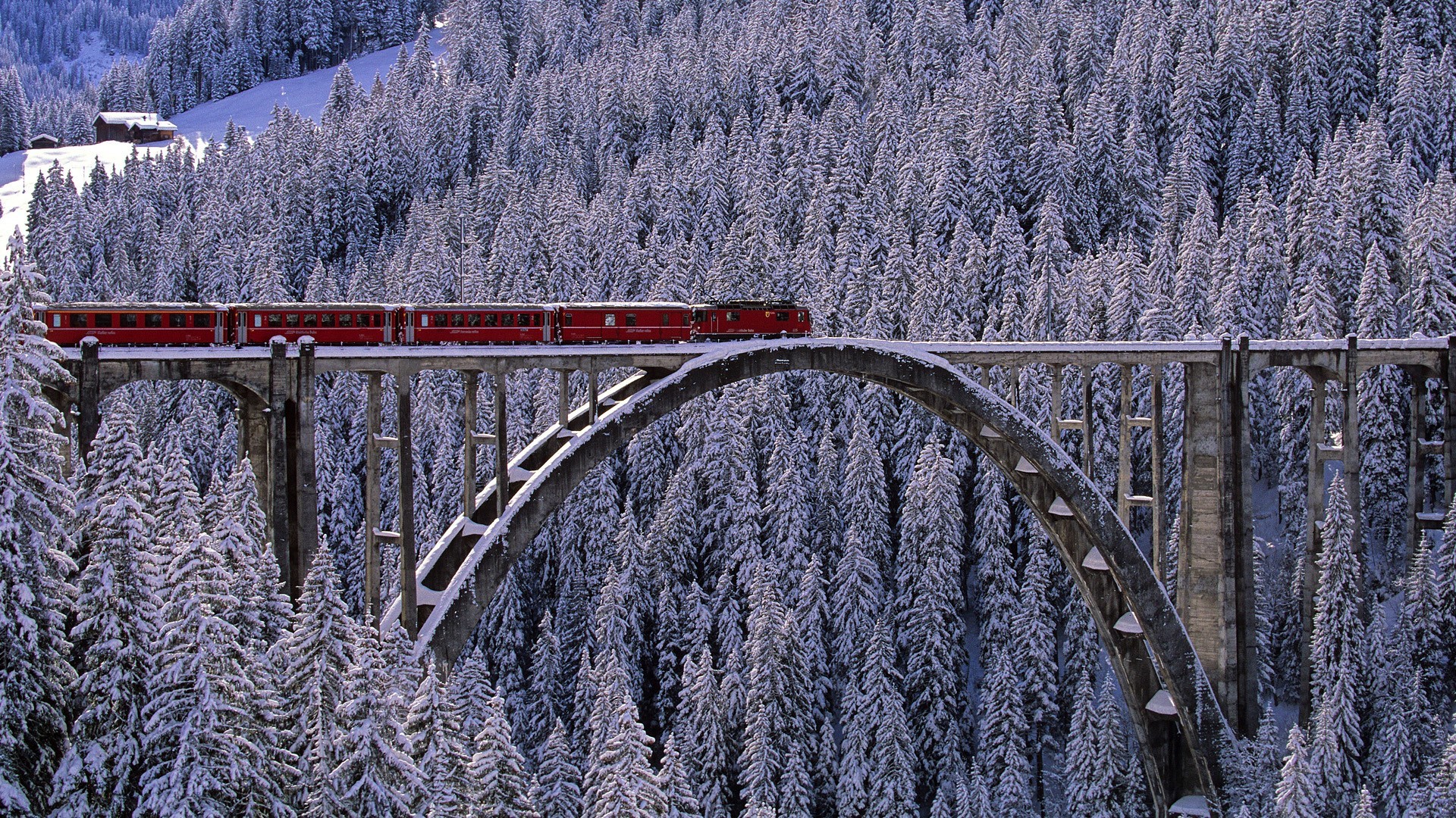 Red train on a snowy bridge in Arosa, Switzerland HD Wallpaper