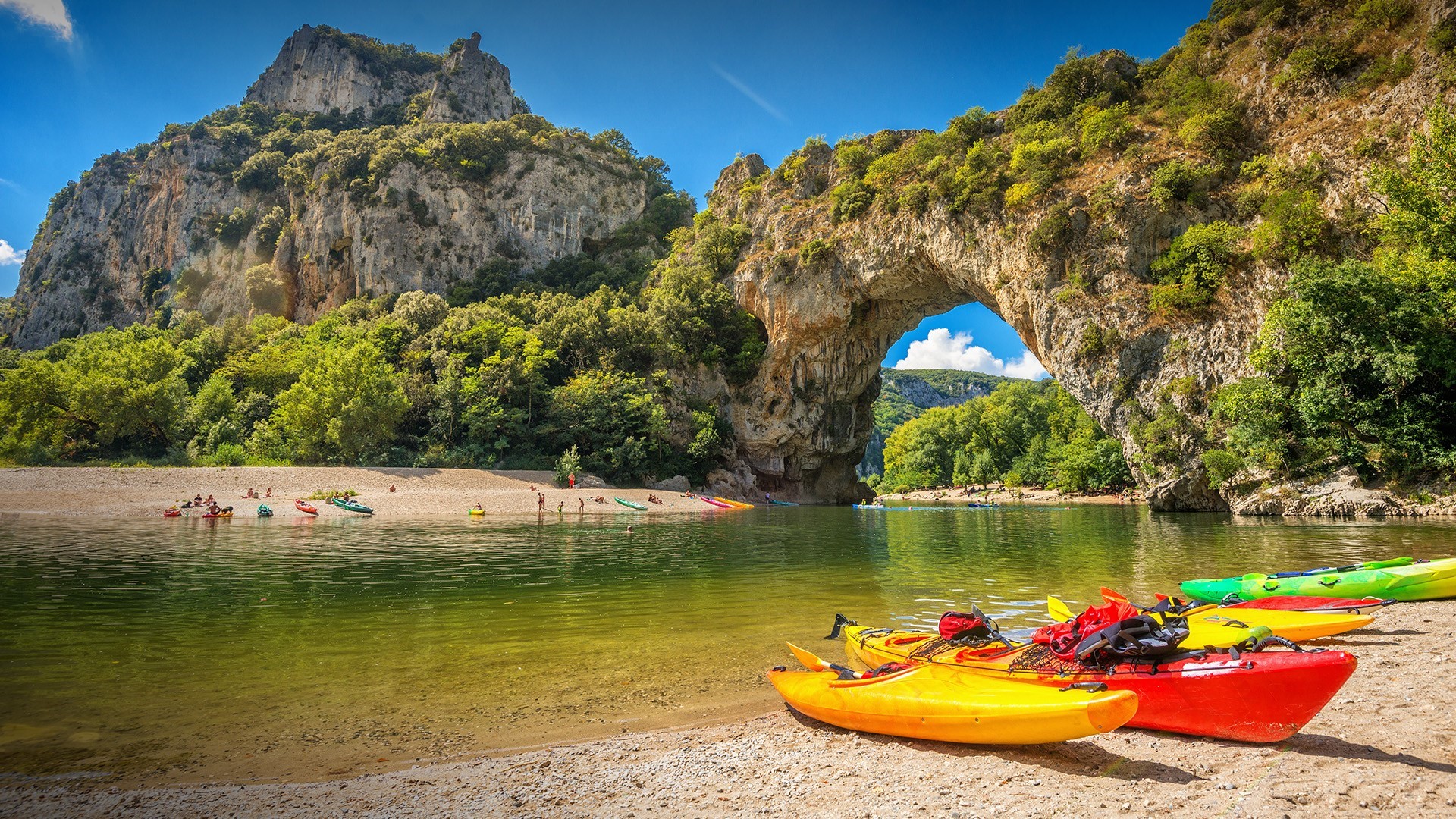 Kayaks on a river with a natural rock arch in France HD Wallpaper