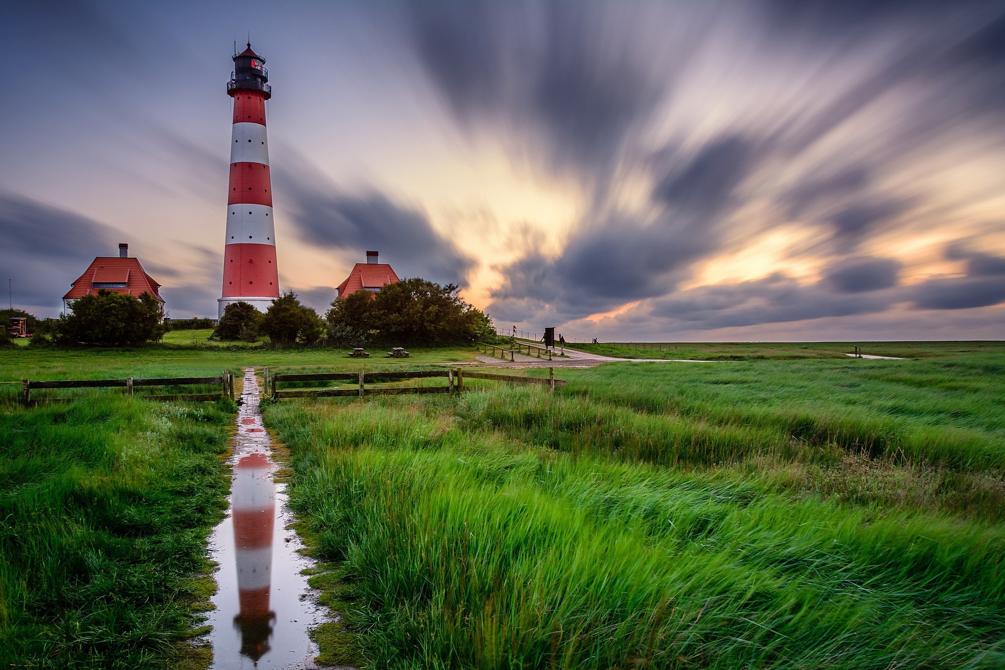 Lighthouse with red and white stripes and reflection in water HD Wallpaper