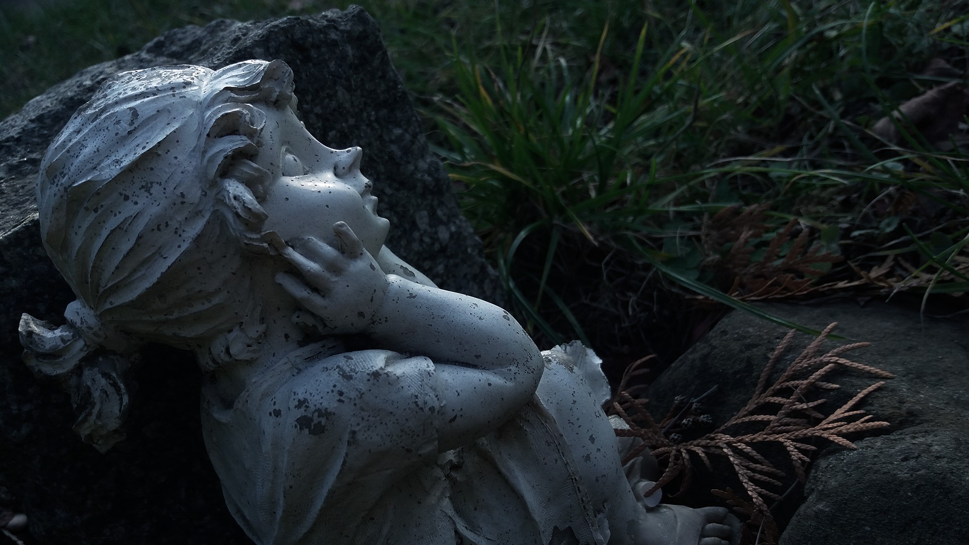 Stone statue of a child in grass HD Wallpaper