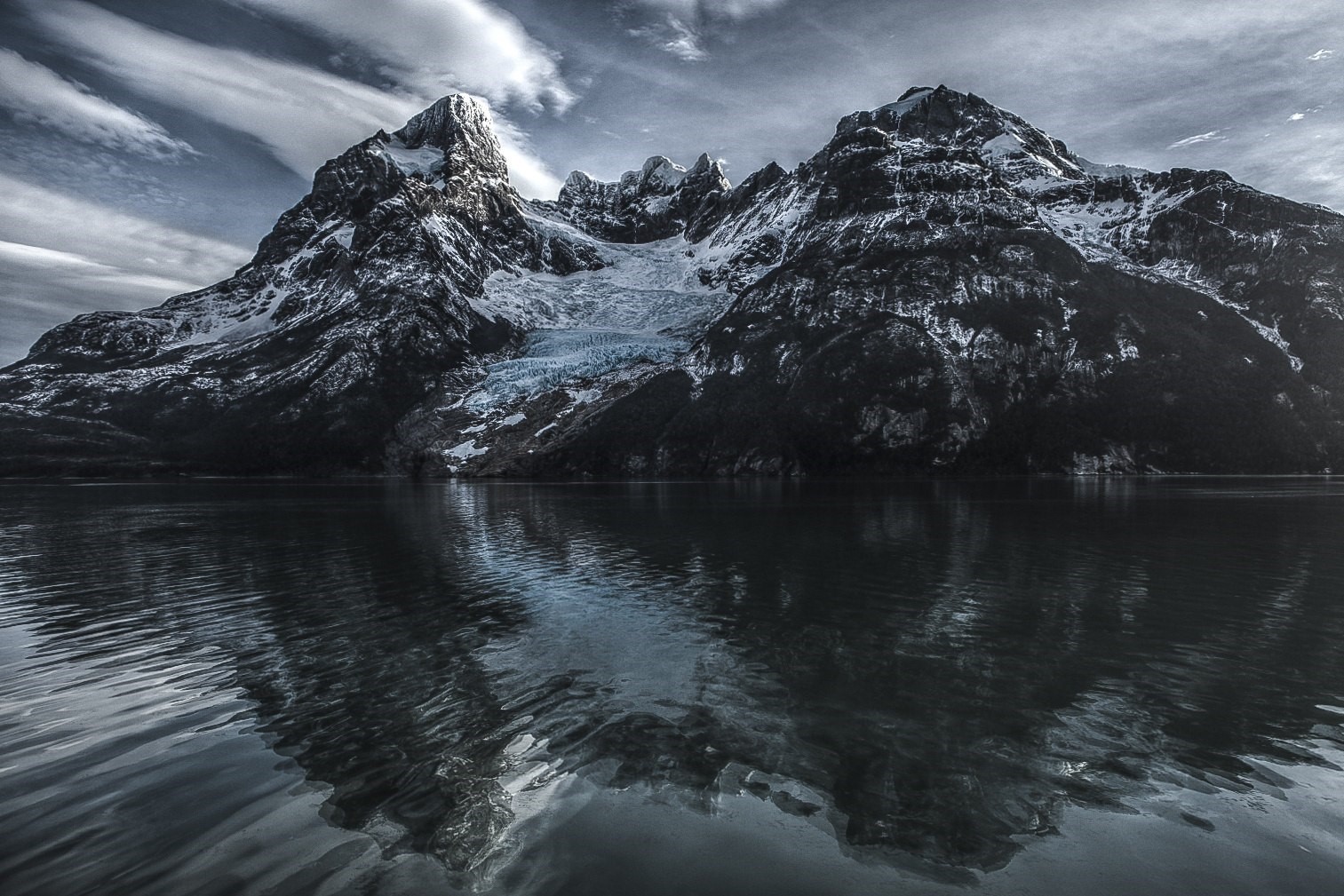 Snow-capped mountains reflected in a dark lake HD Wallpaper