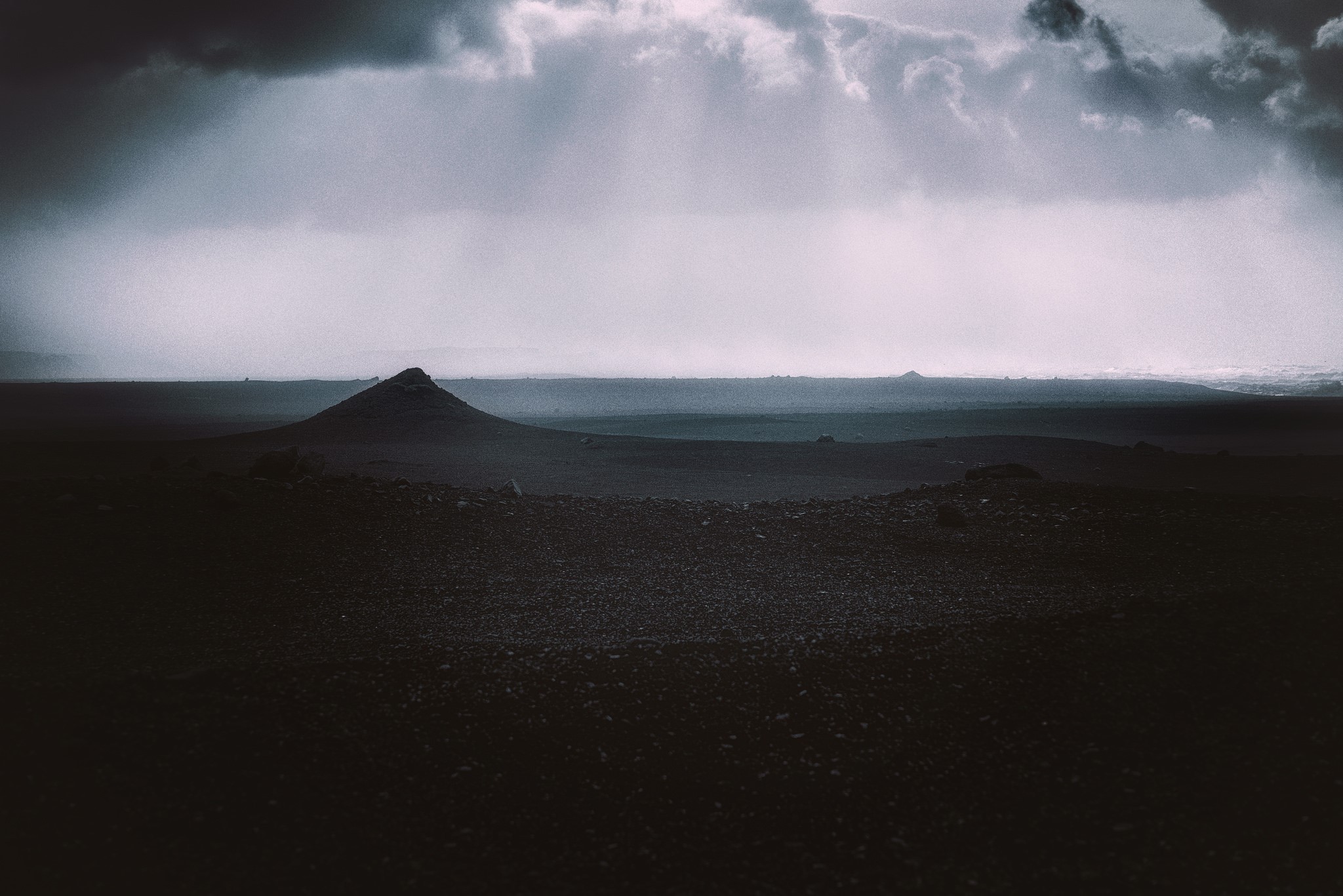 Stormy sky over a desolate volcanic landscape HD Wallpaper