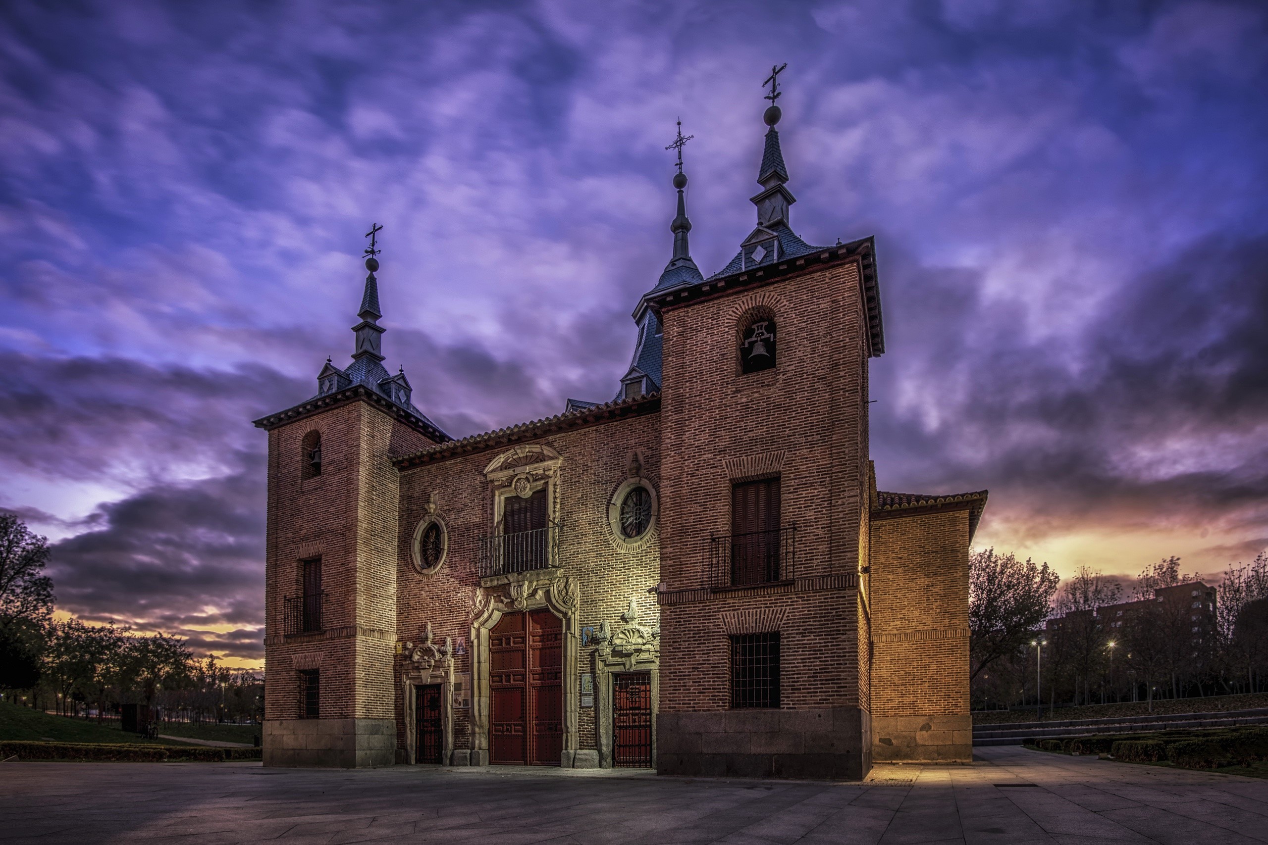 Brick church with spires against a dramatic purple sky HD Wallpaper