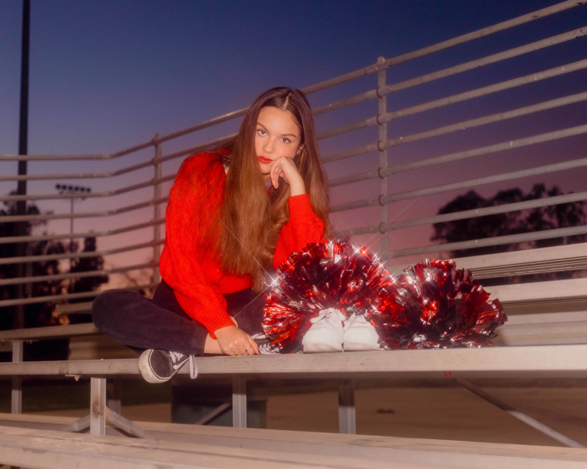 Olivia Rodrigo sitting on bleachers with pom-poms HD Wallpaper