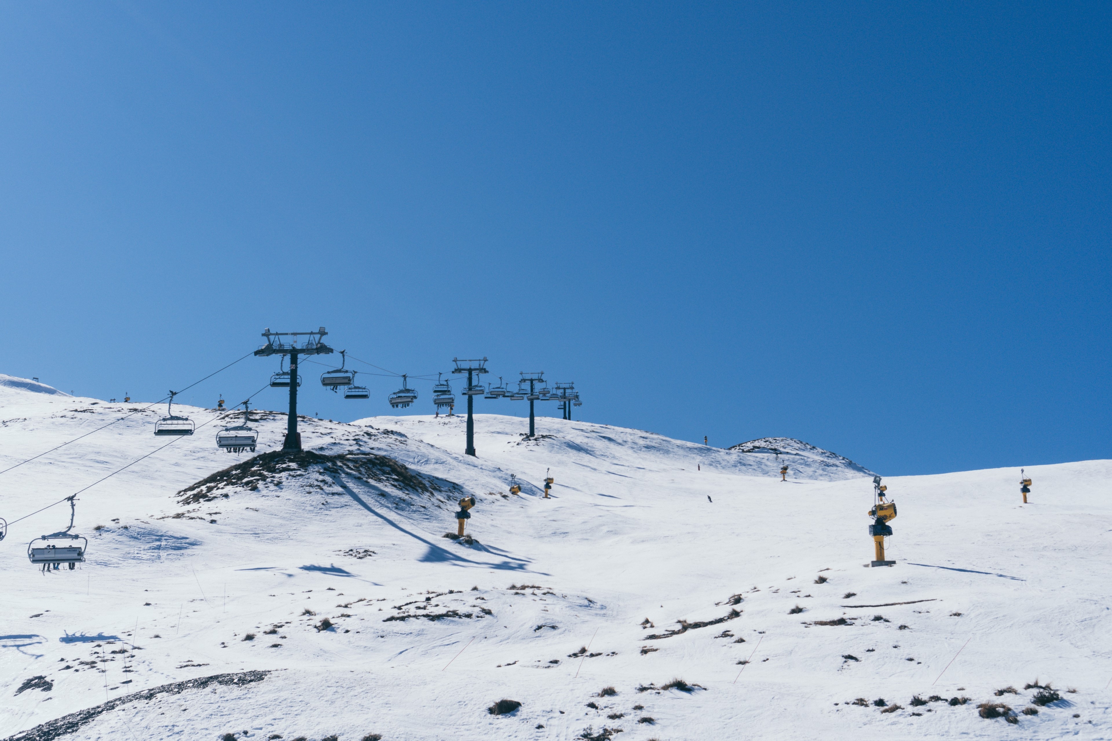Ski resort with chairlifts on snowy mountains under blue sky HD Wallpaper