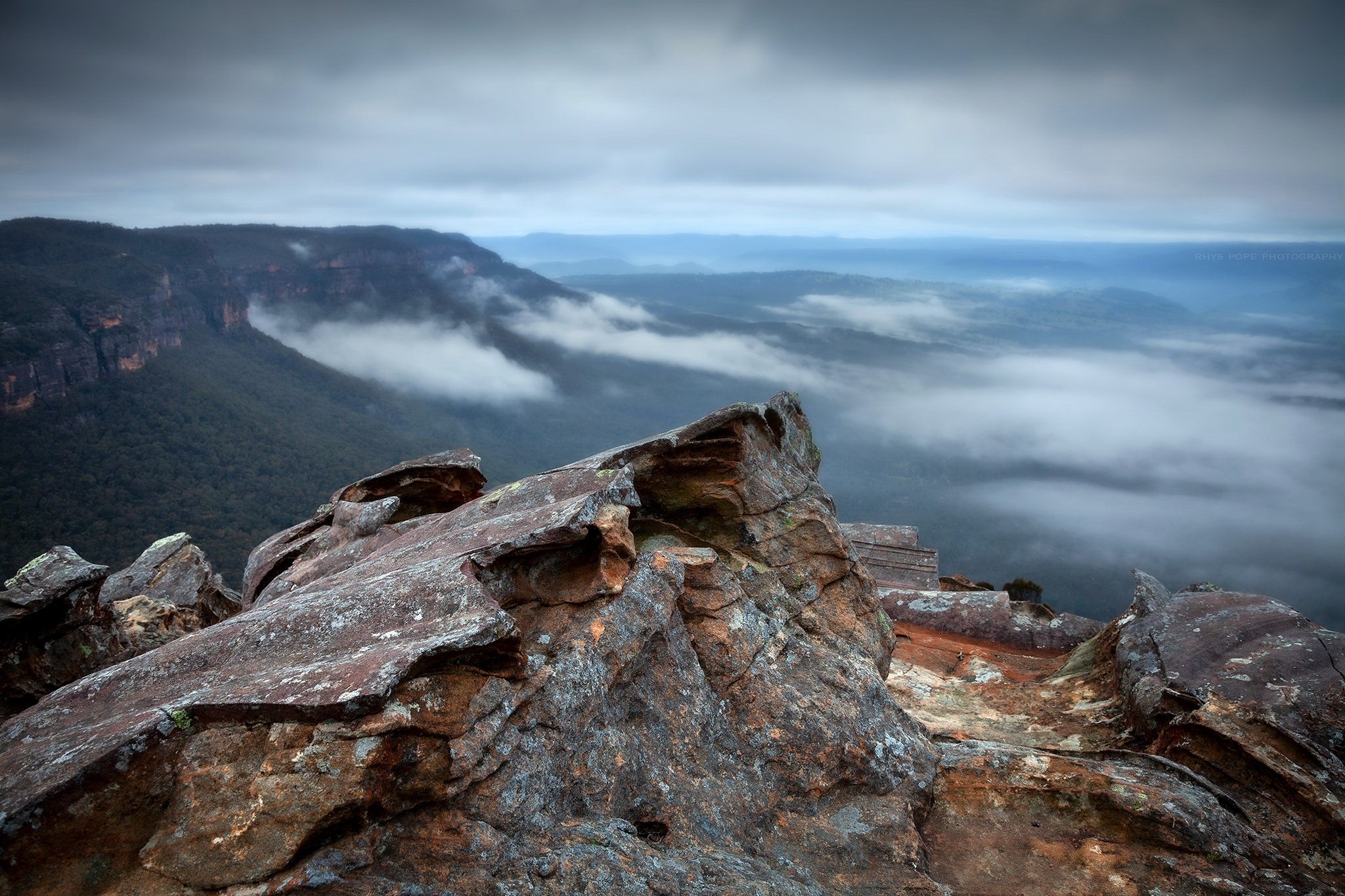 Rocky outcrop overlooking misty Blue Mountains landscape HD Wallpaper