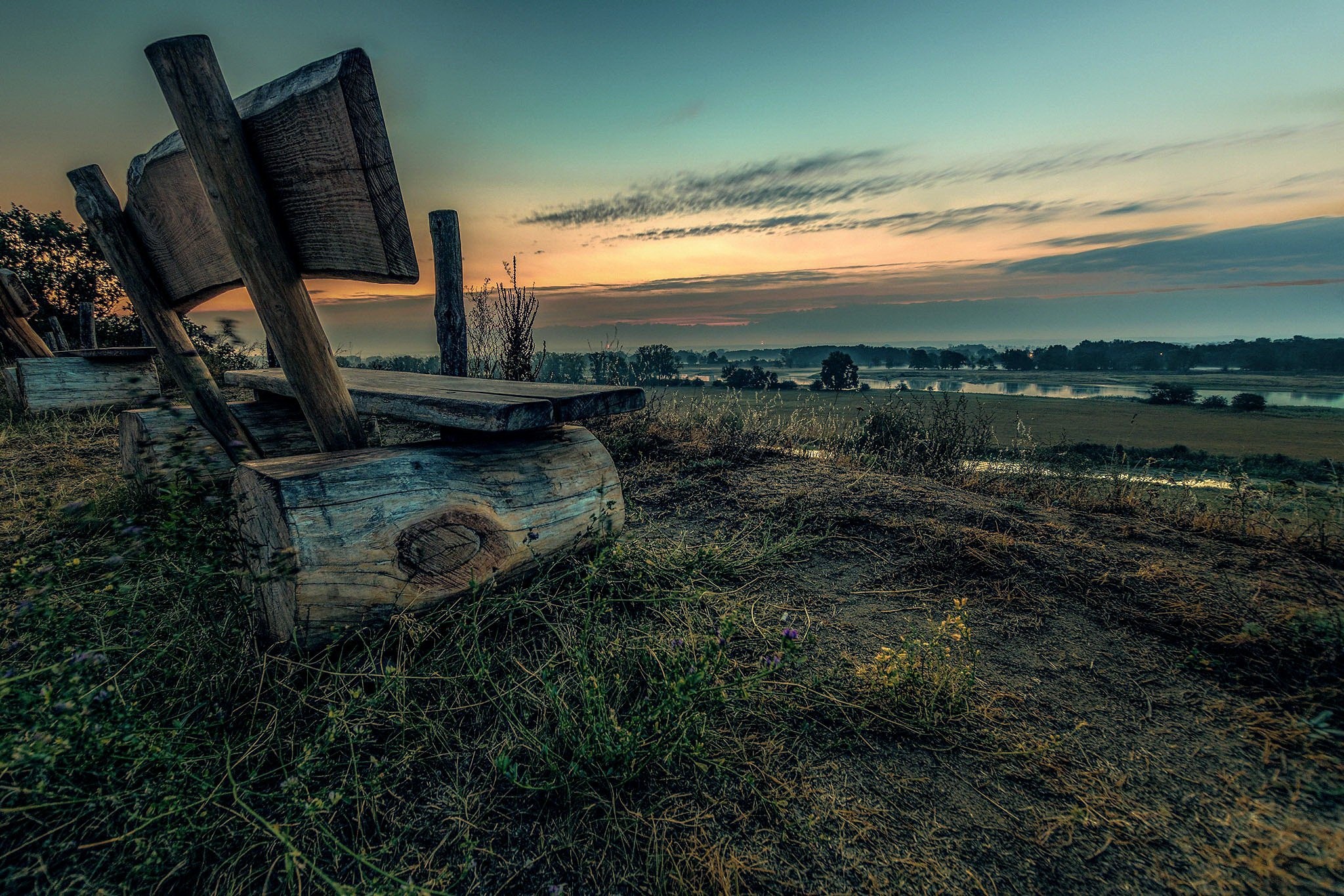 Wooden bench overlooking a misty landscape at sunset HD Wallpaper